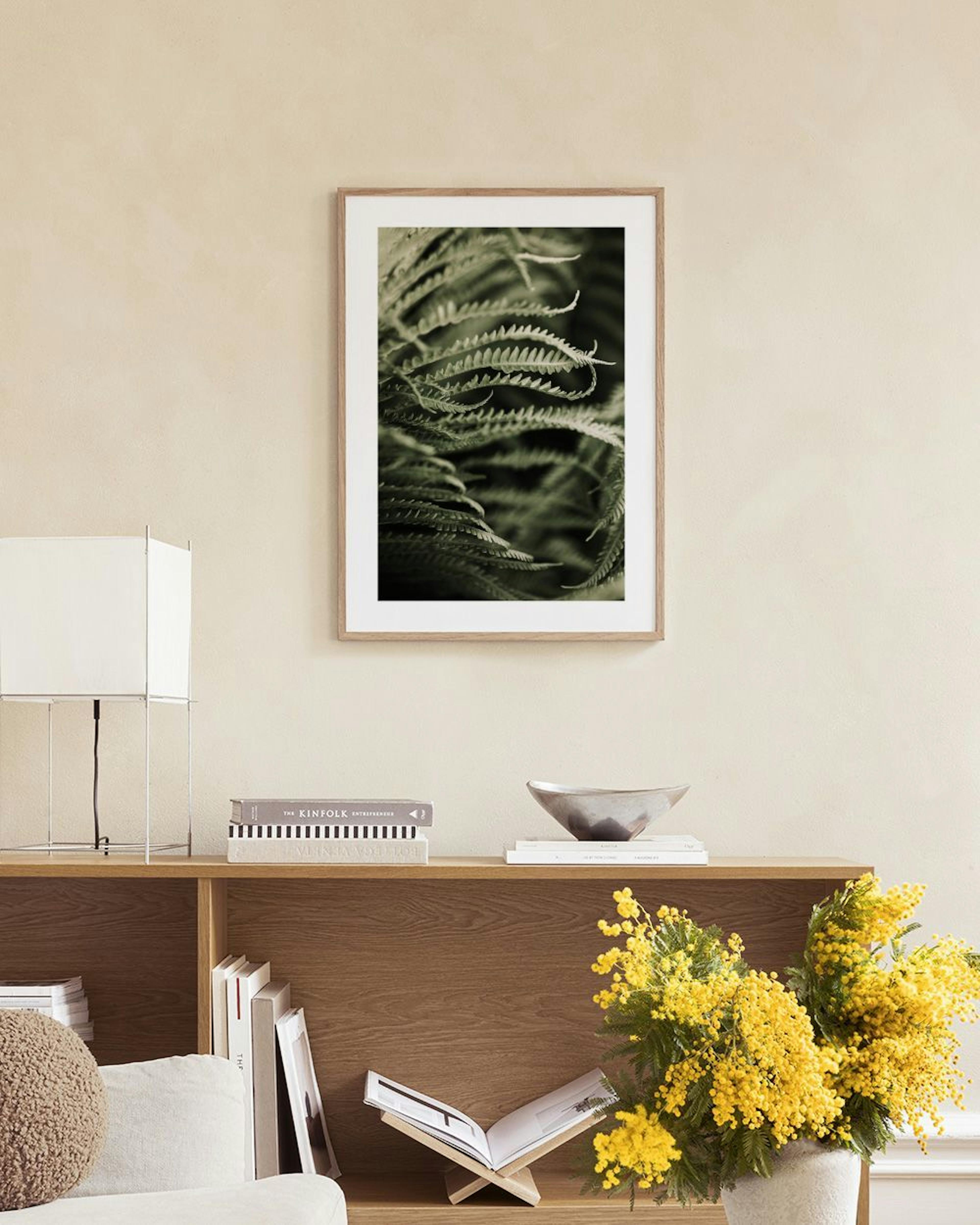 Poster van donkergroene varenbladeren, hangend boven een wit marmeren tafeltje met vazen en boeken.