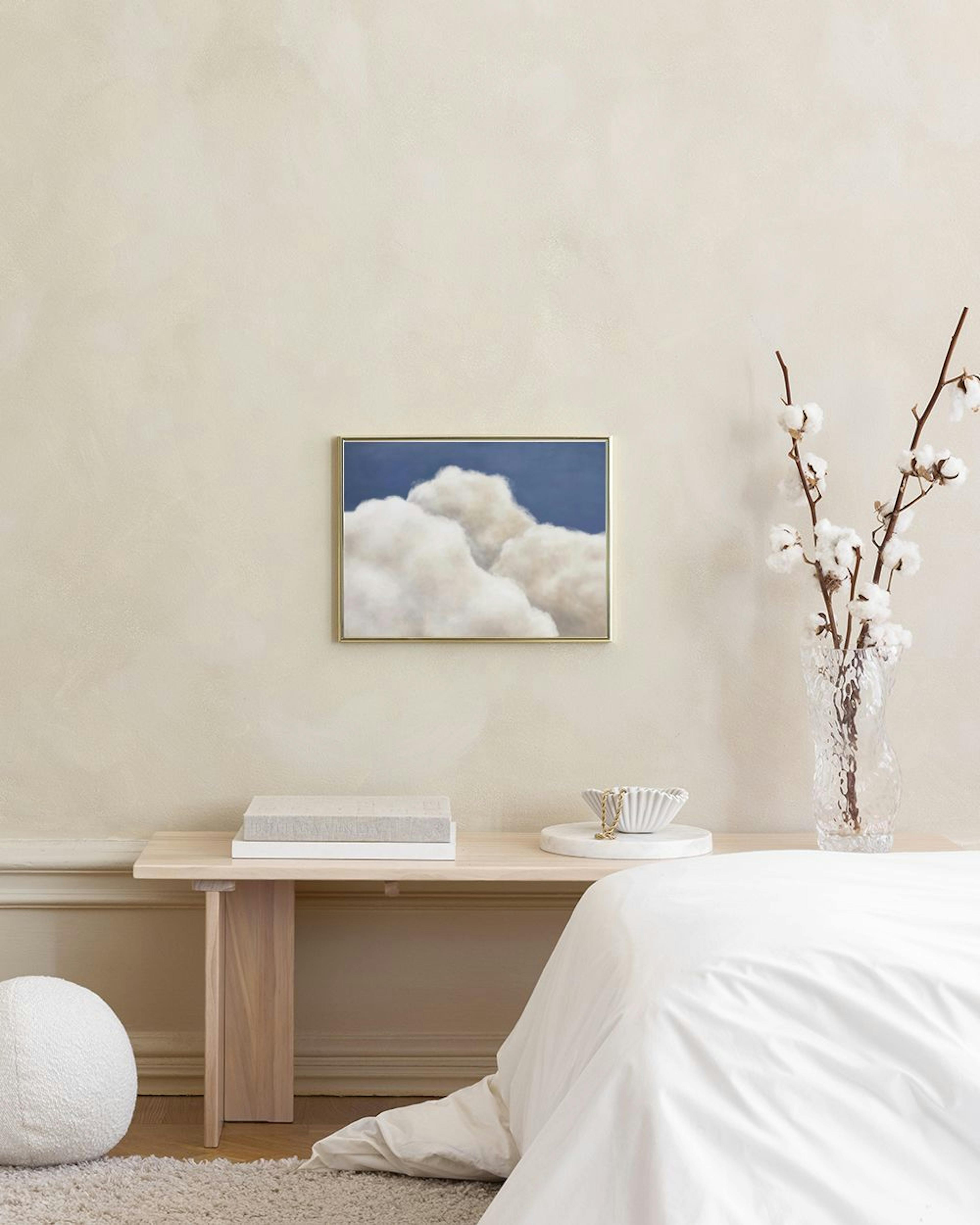 Poster mit weißen Wolken vor blauem Himmel, hängend über einem Holztisch mit Gläsern und Nüssen.
