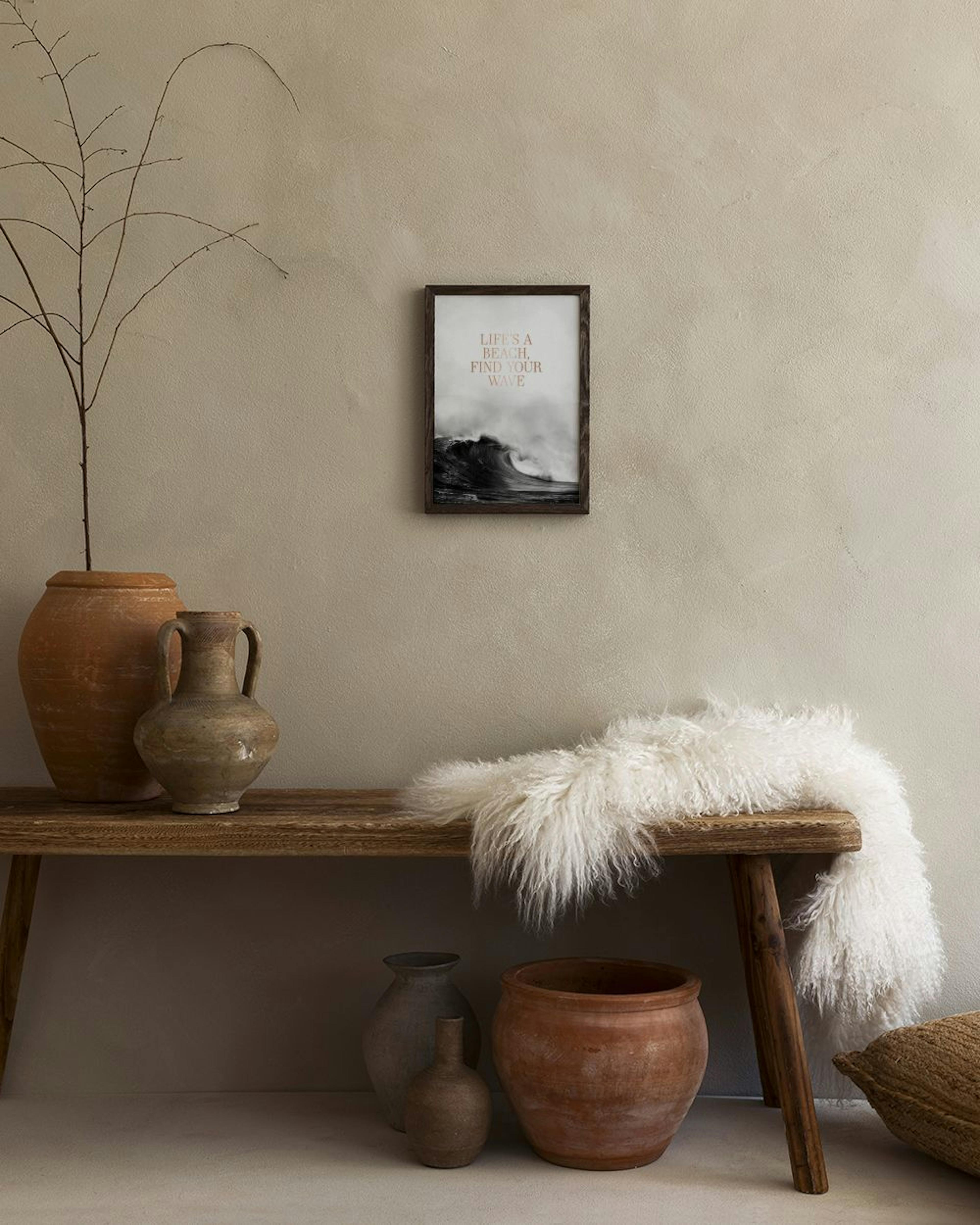 En plakat med en stor, sort/hvid bølge og tekst LIFES A BEACH, FIND YOUR WAVE hænger på en grå væg over to sofaborde i moderne s