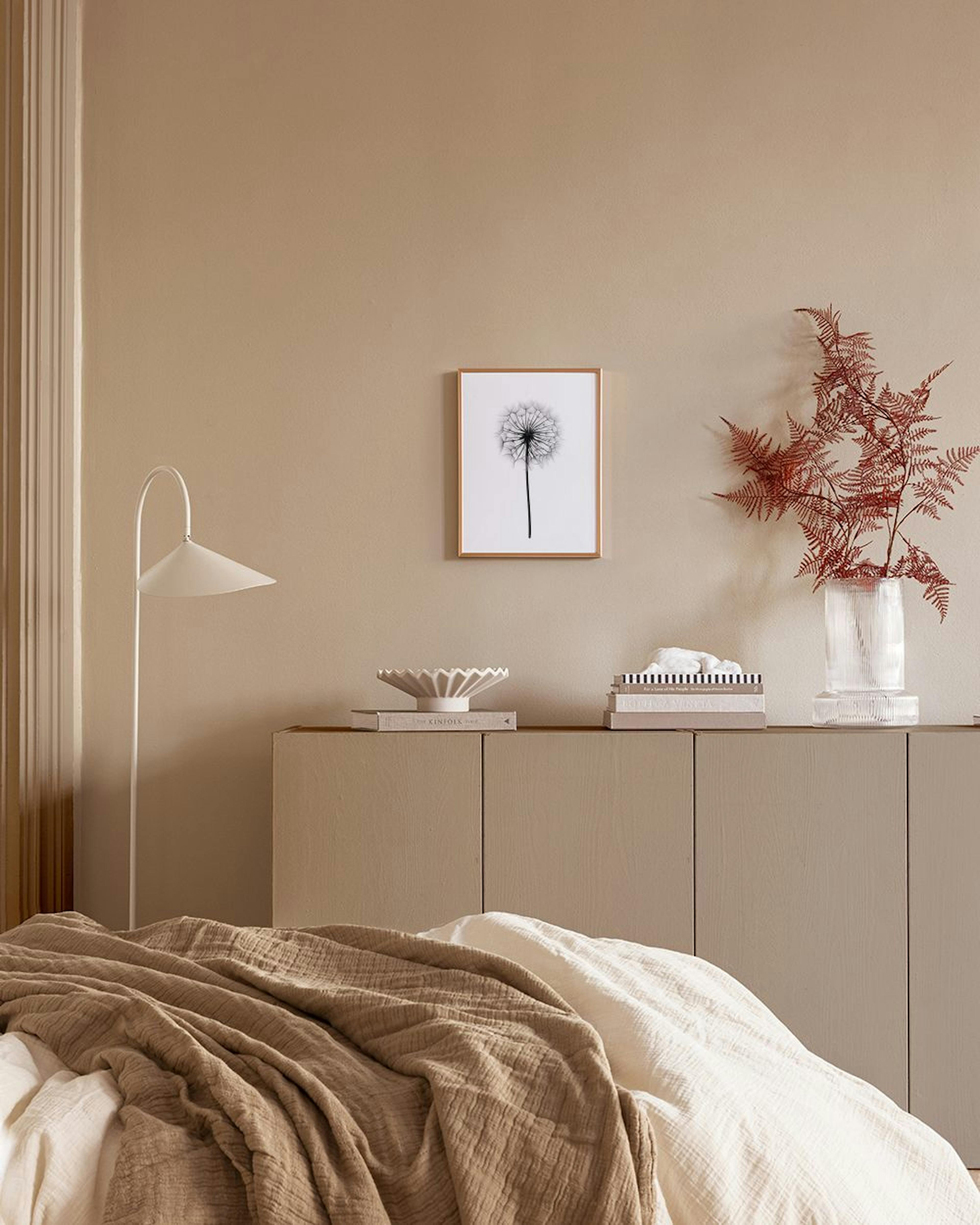 A black and white dandelion seed head print hanging above a wooden shelf with white and gray vases against a blue wall.