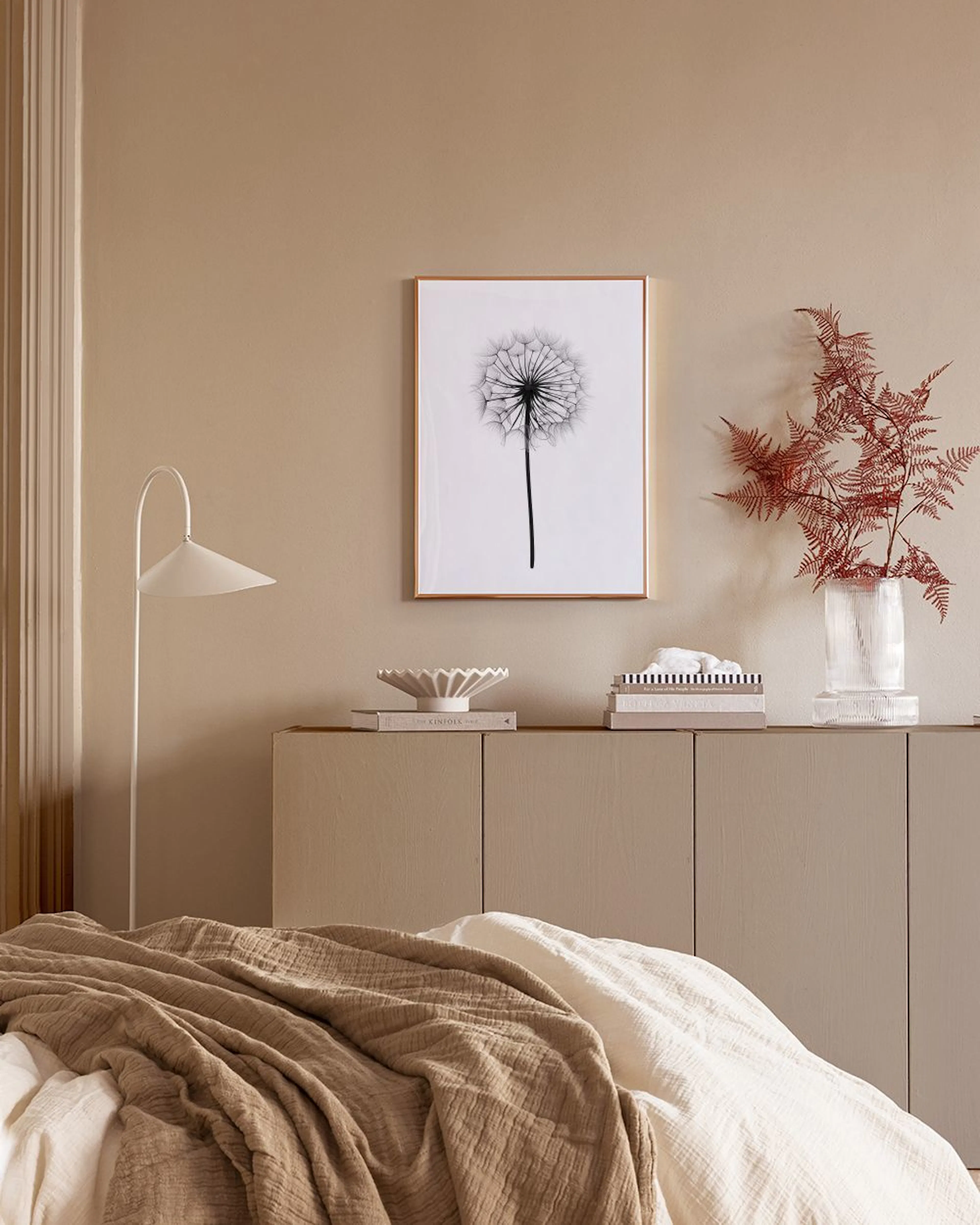 Affiche de fleur de pissenlit noire et blanche sur mur bleu, avec des vases blancs sur une étagère.