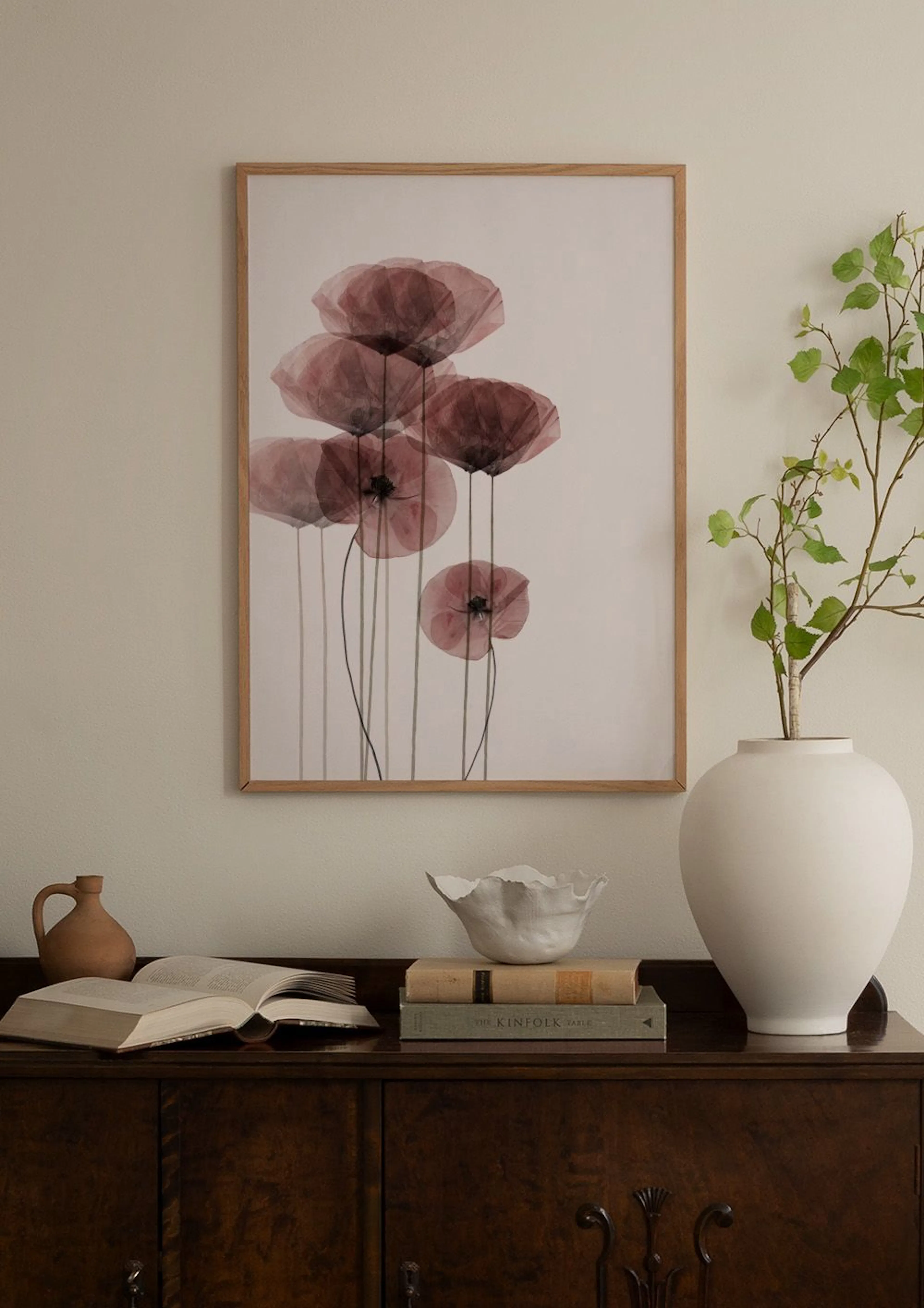 Wohnzimmer mit Galerie Wand aus Postern mit abstrakten Formen in Terrakotta, Beige, Schwarz und Weiß über einem bordeauxroten So