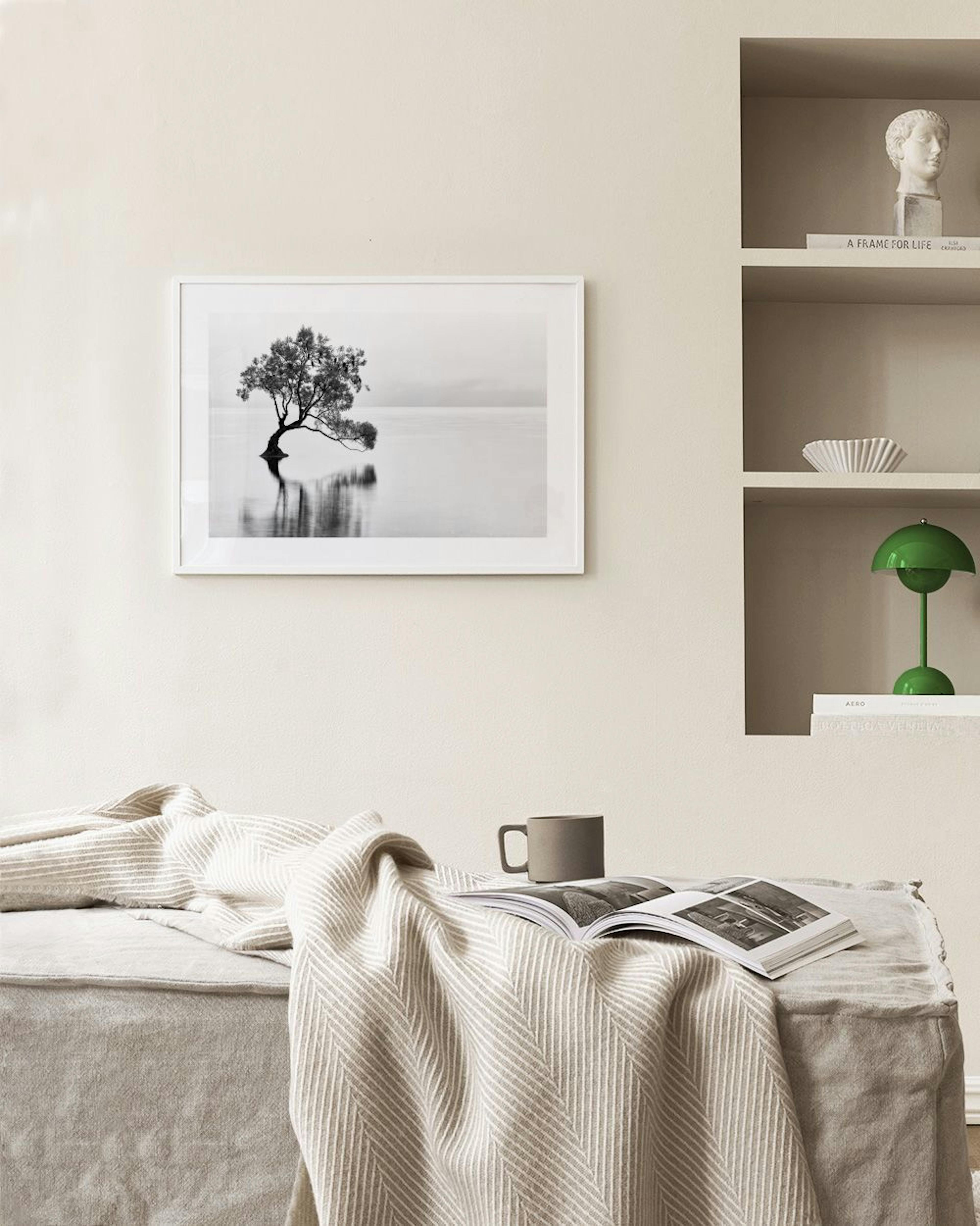 En sort-hvid plakat af et træ i vandet med refleksioner, hængende over en mintgrøn stol i en stue.