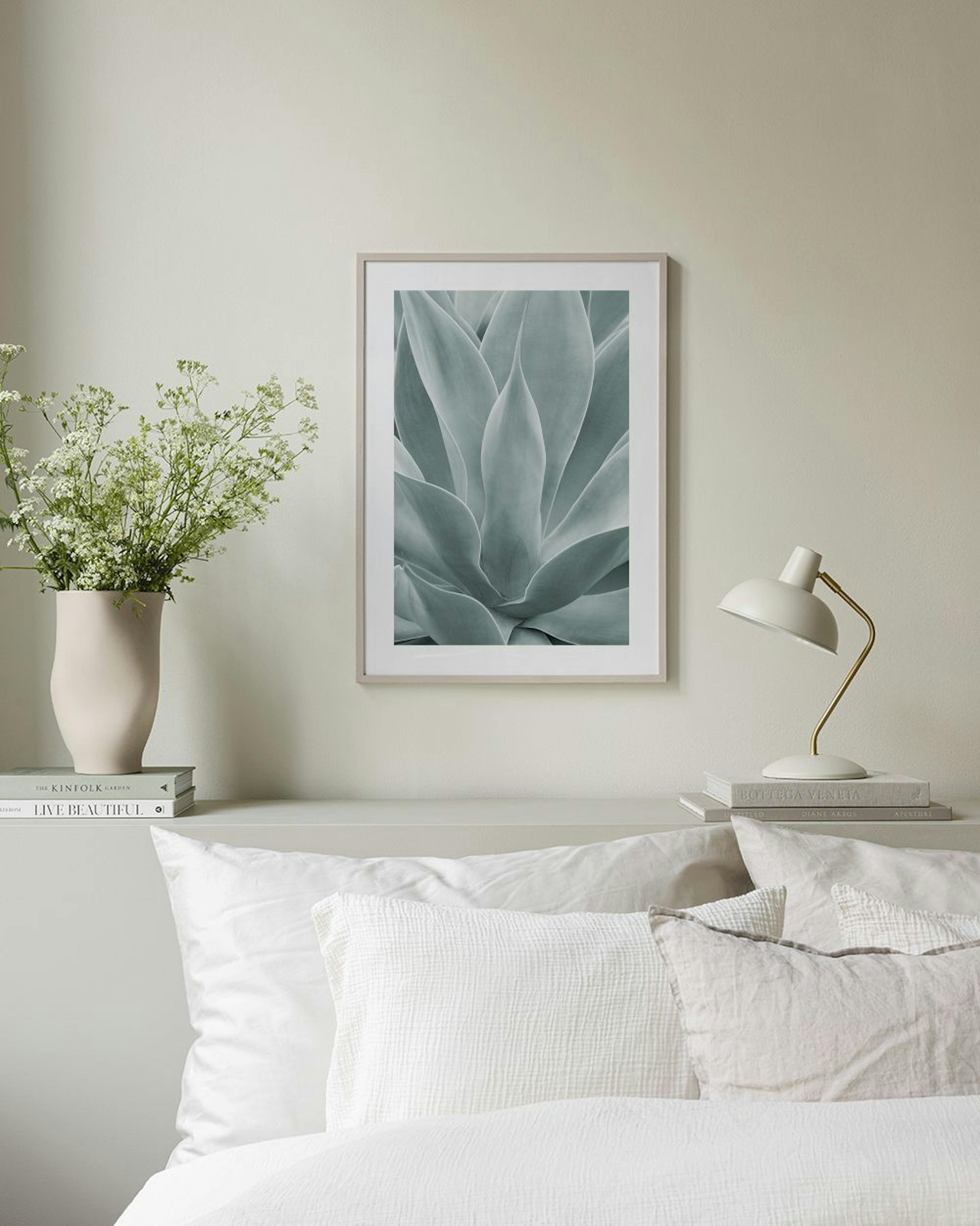 Póster de planta suculenta en blanco y negro, colgado sobre un mueble blanco con un jarrón redondo y un sillón verde.