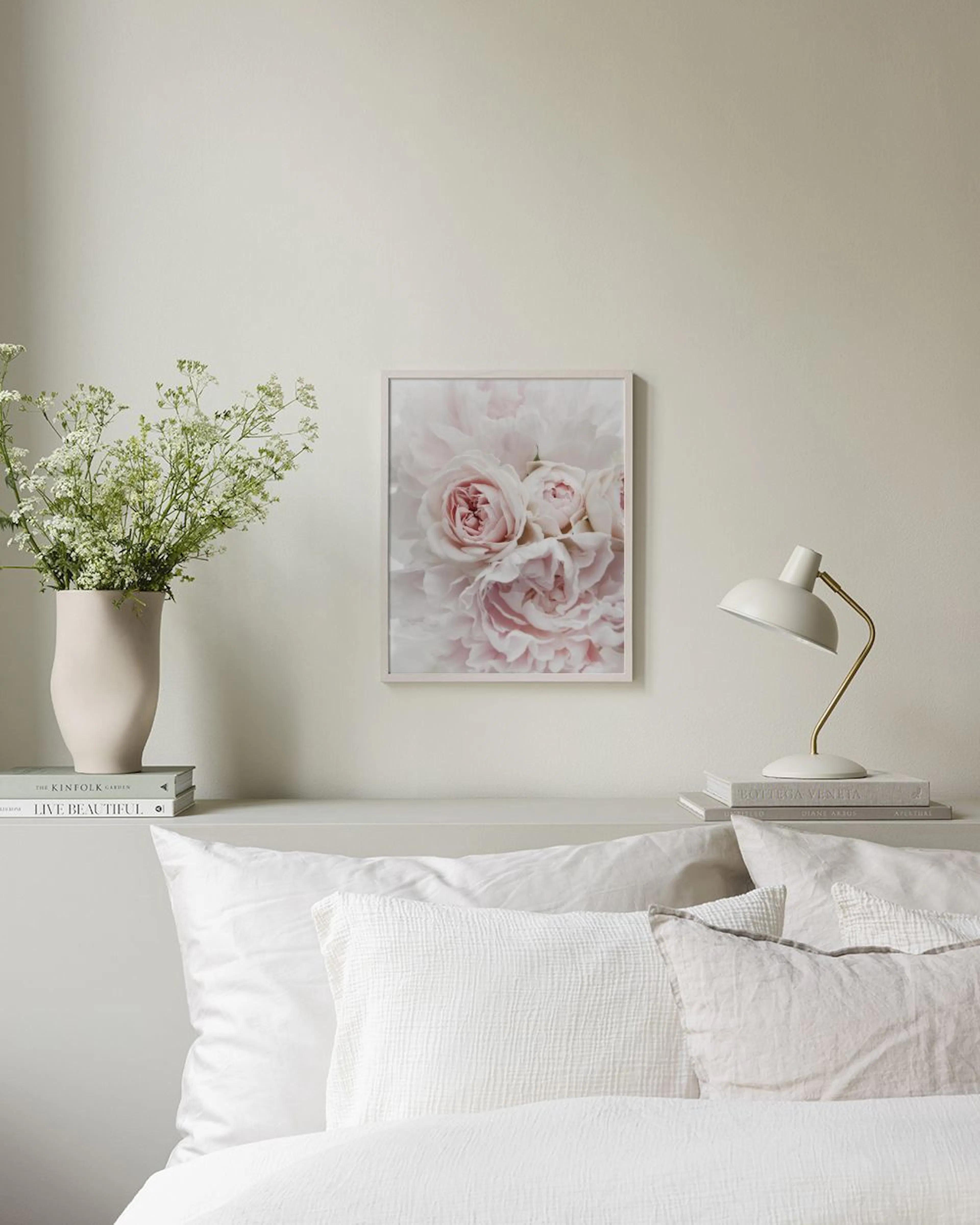 Póster de peonías y rosas rosadas pálidas, exhibido sobre un gabinete gris con jarrones y libros en una habitación luminosa.