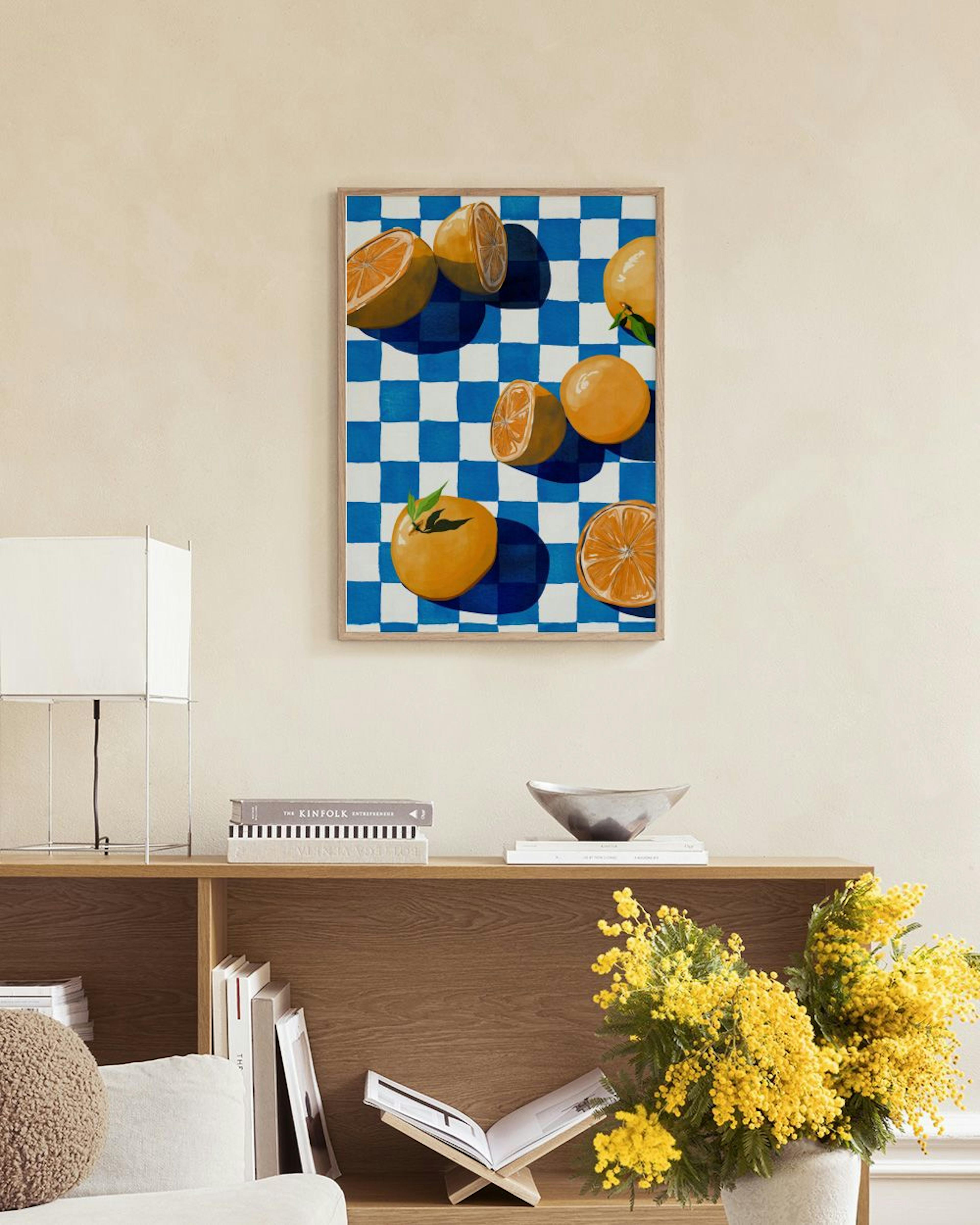 A print of oranges and sliced oranges on a blue and white checkered background, hanging above a sofa in a modern living room.