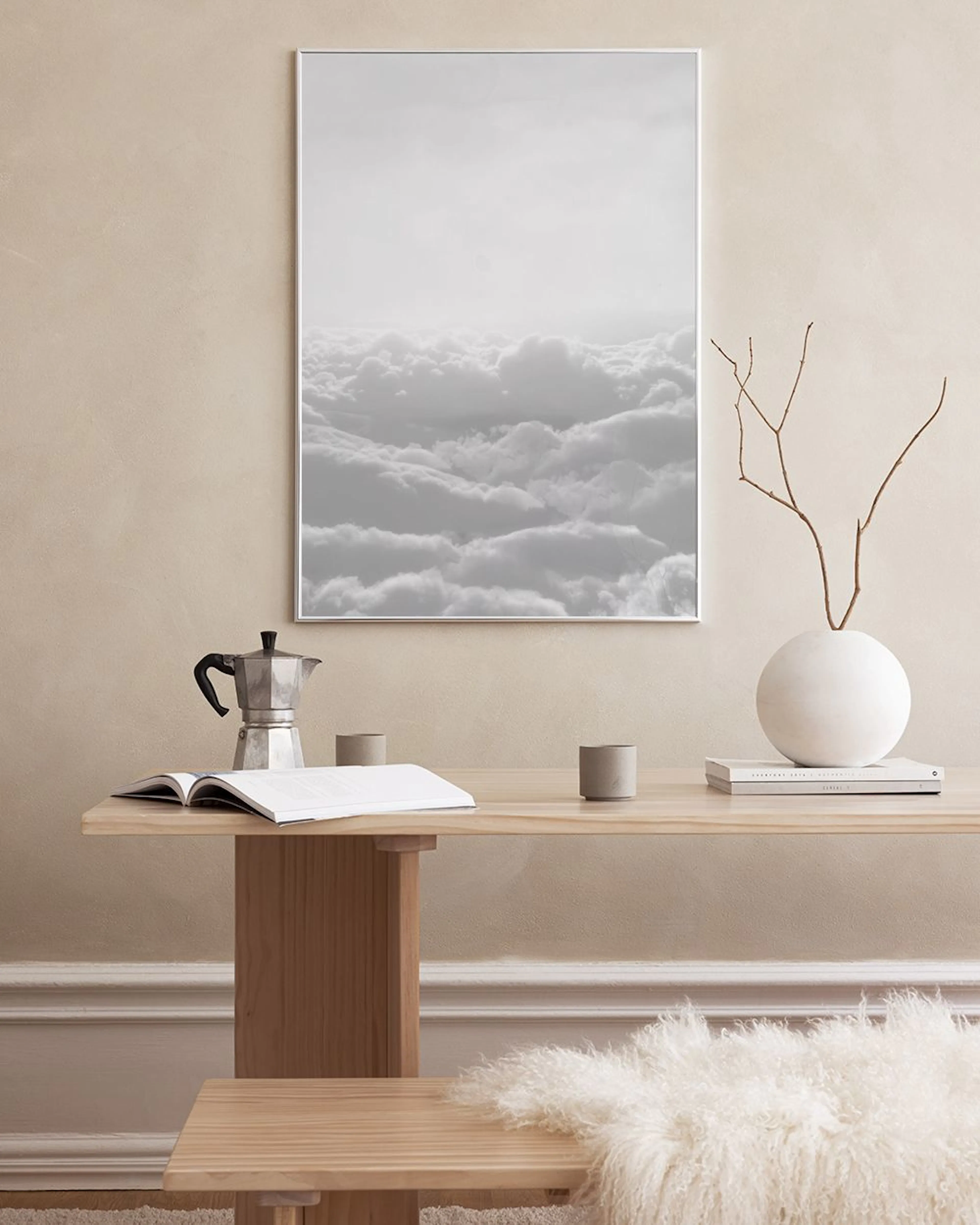 Affiche noir et blanc de nuages, accrochée sur un mur foncé au-dessus de piles de magazines et de poupées Matriochka.