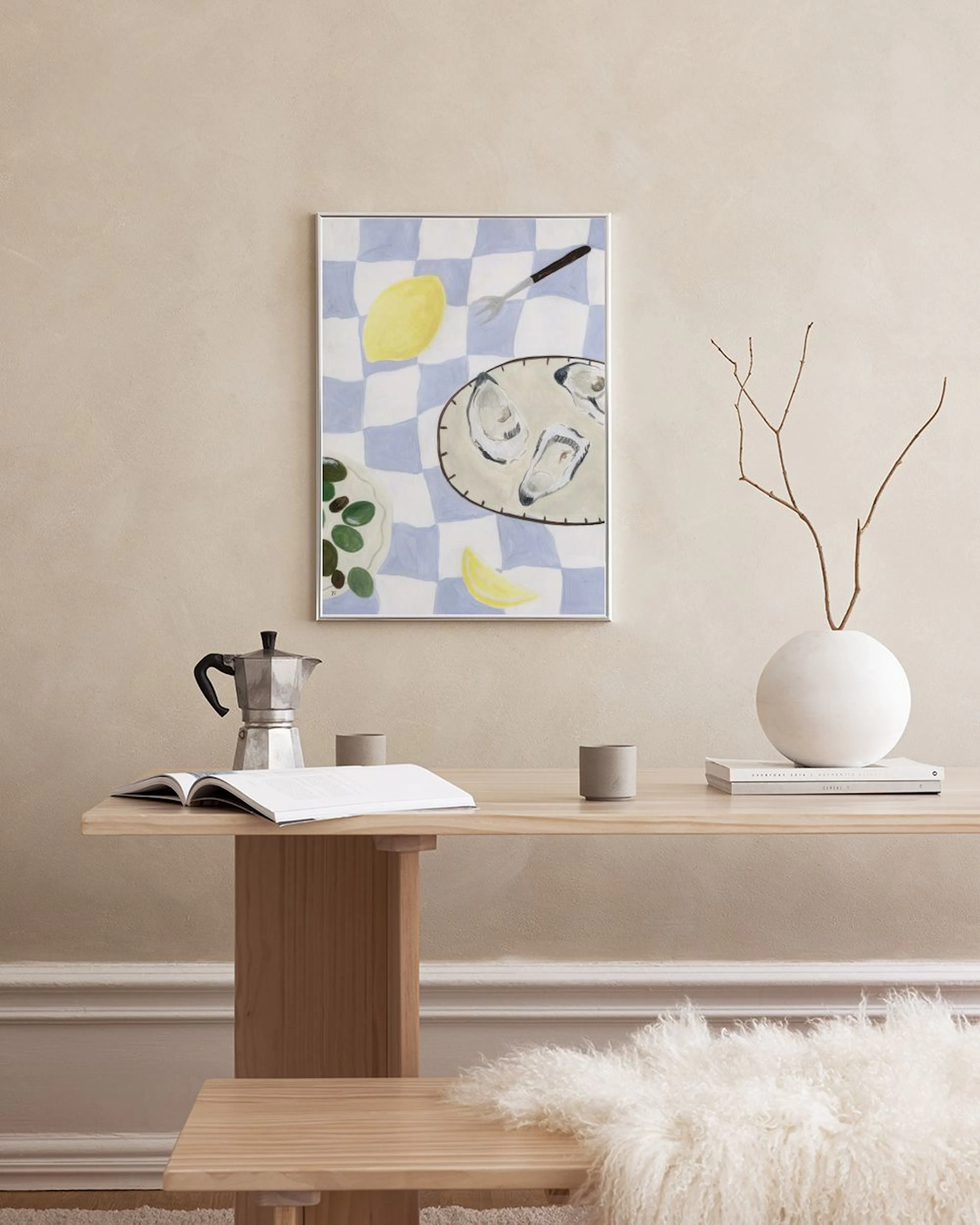 Póster de estilo pictórico con un mantel de cuadros azules y blancos, ostras, limón y un tenedor, colgado en una sala de estar.