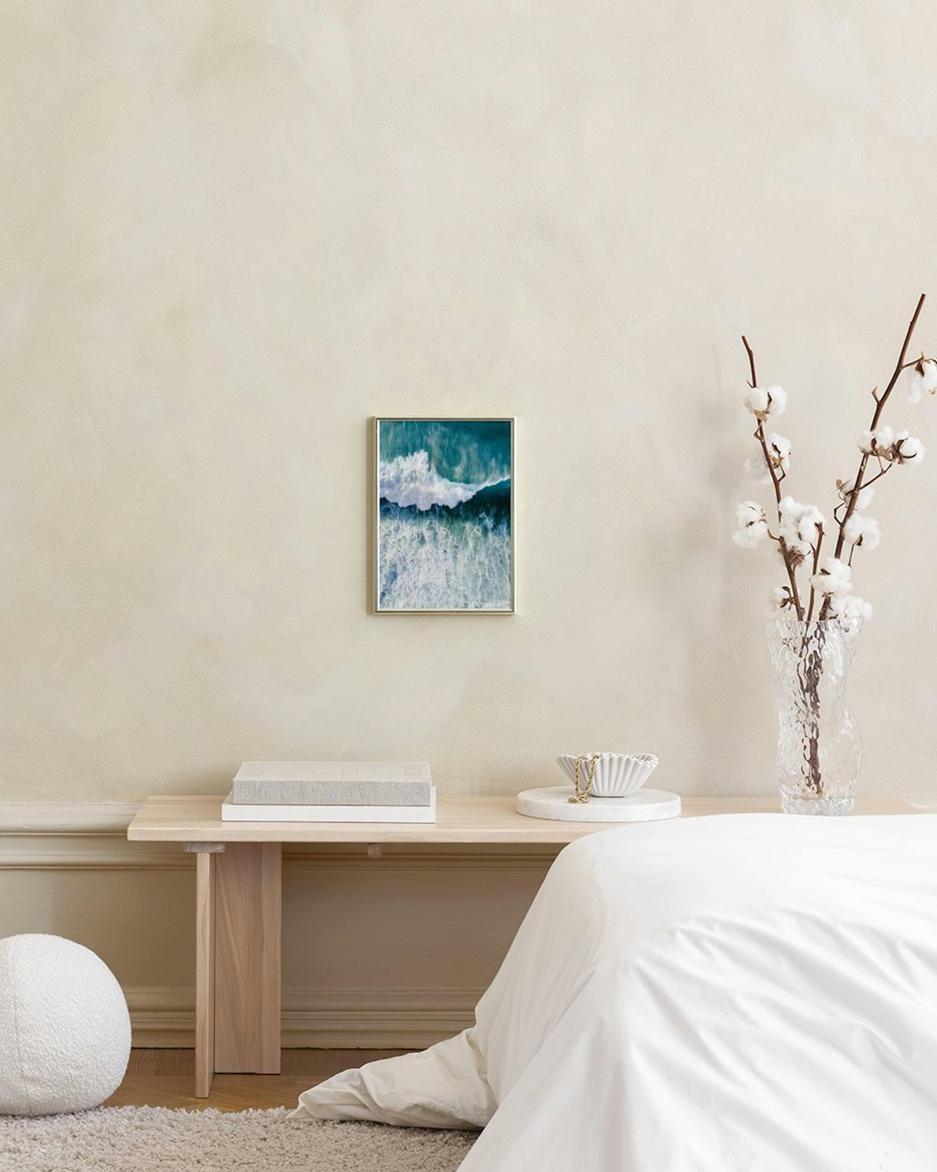 Affiche murale de vagues docéan turquoise avec écume blanche, suspendue dans un intérieur lumineux au-dessus dun meuble blanc.