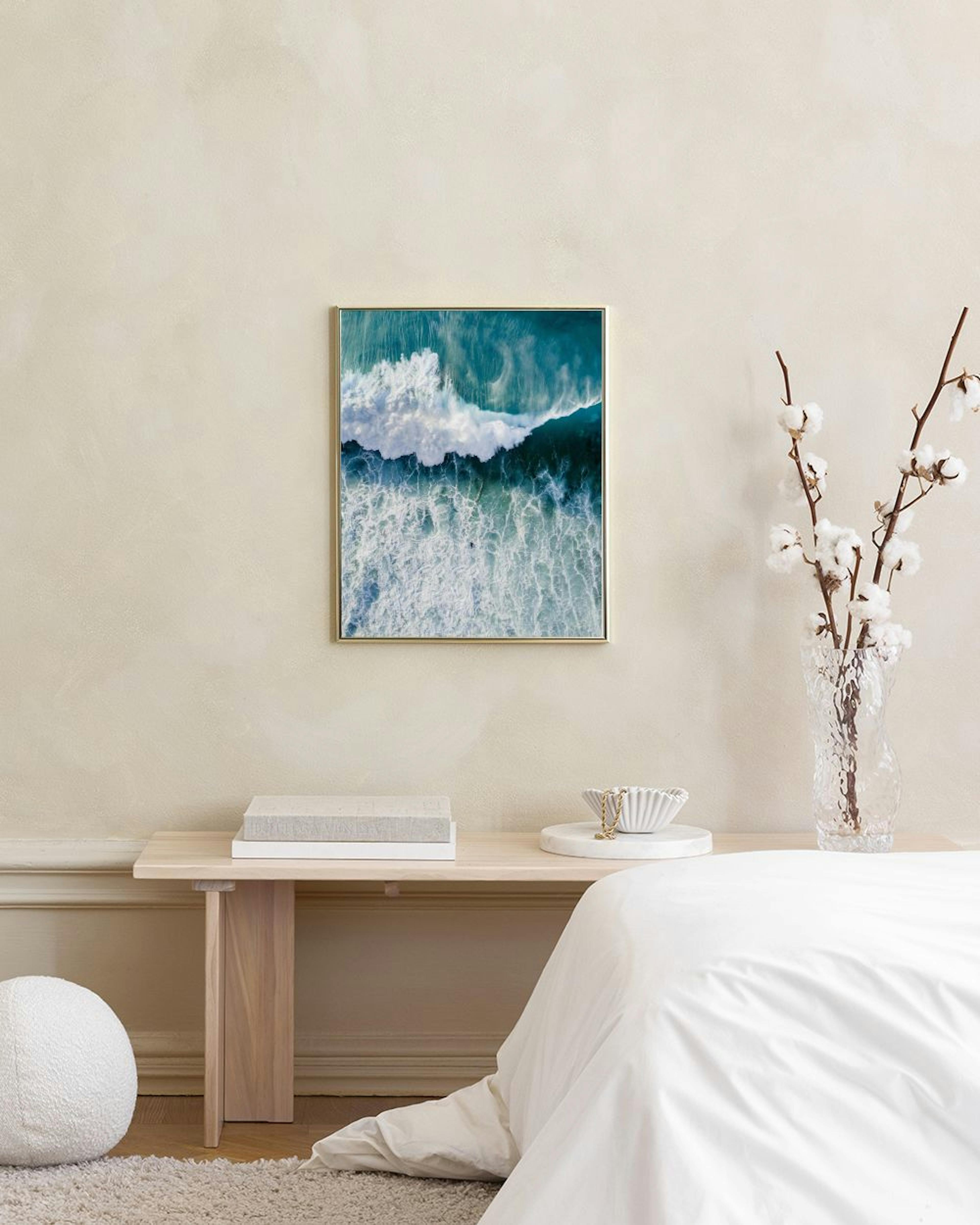 Ocean wave print with foamy white surf and deep blue-green water, displayed above a white console table in a minimalist room.
