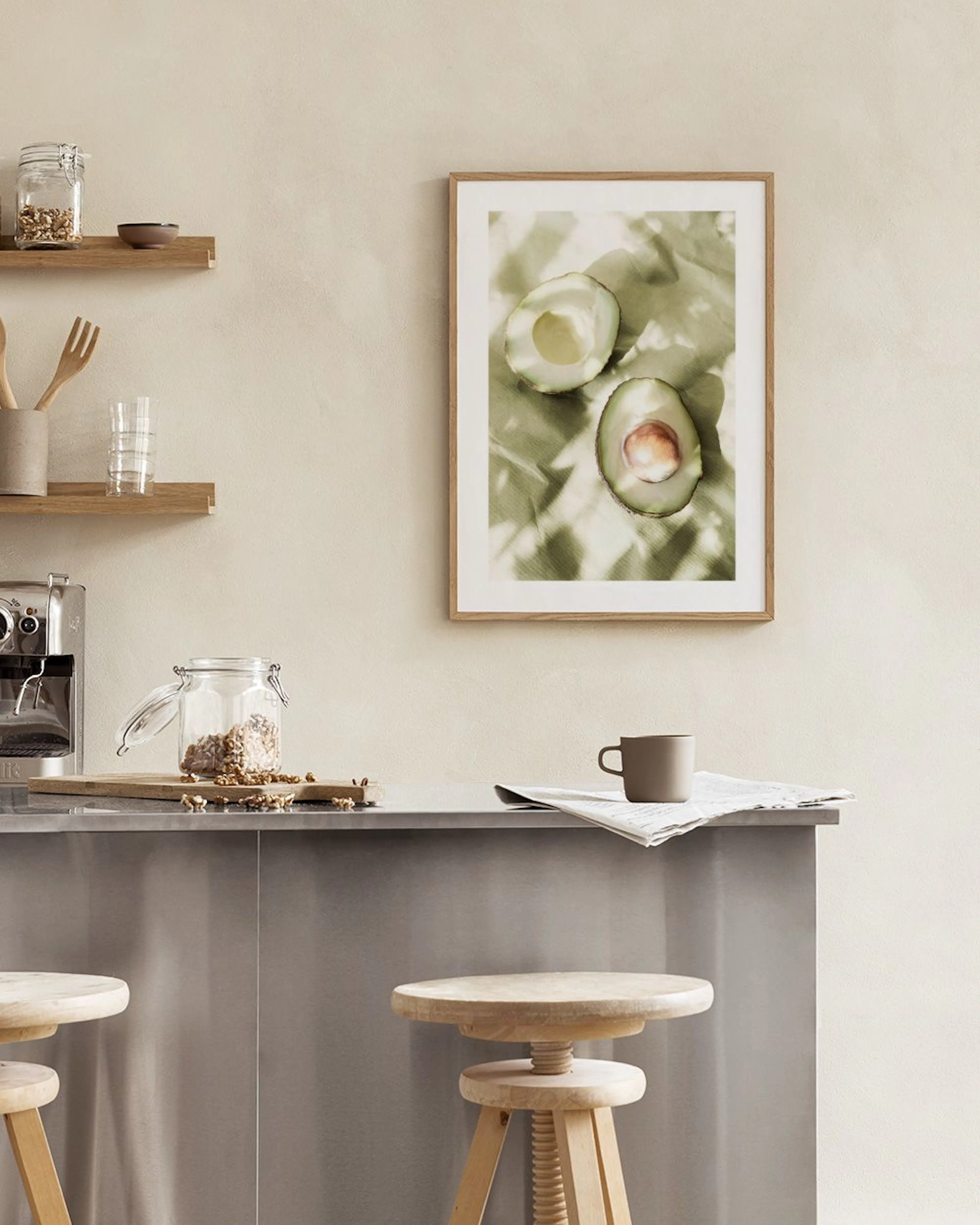 Poster van twee halve avocados op een groene ondergrond, hangend boven een witte ladekast met servies.