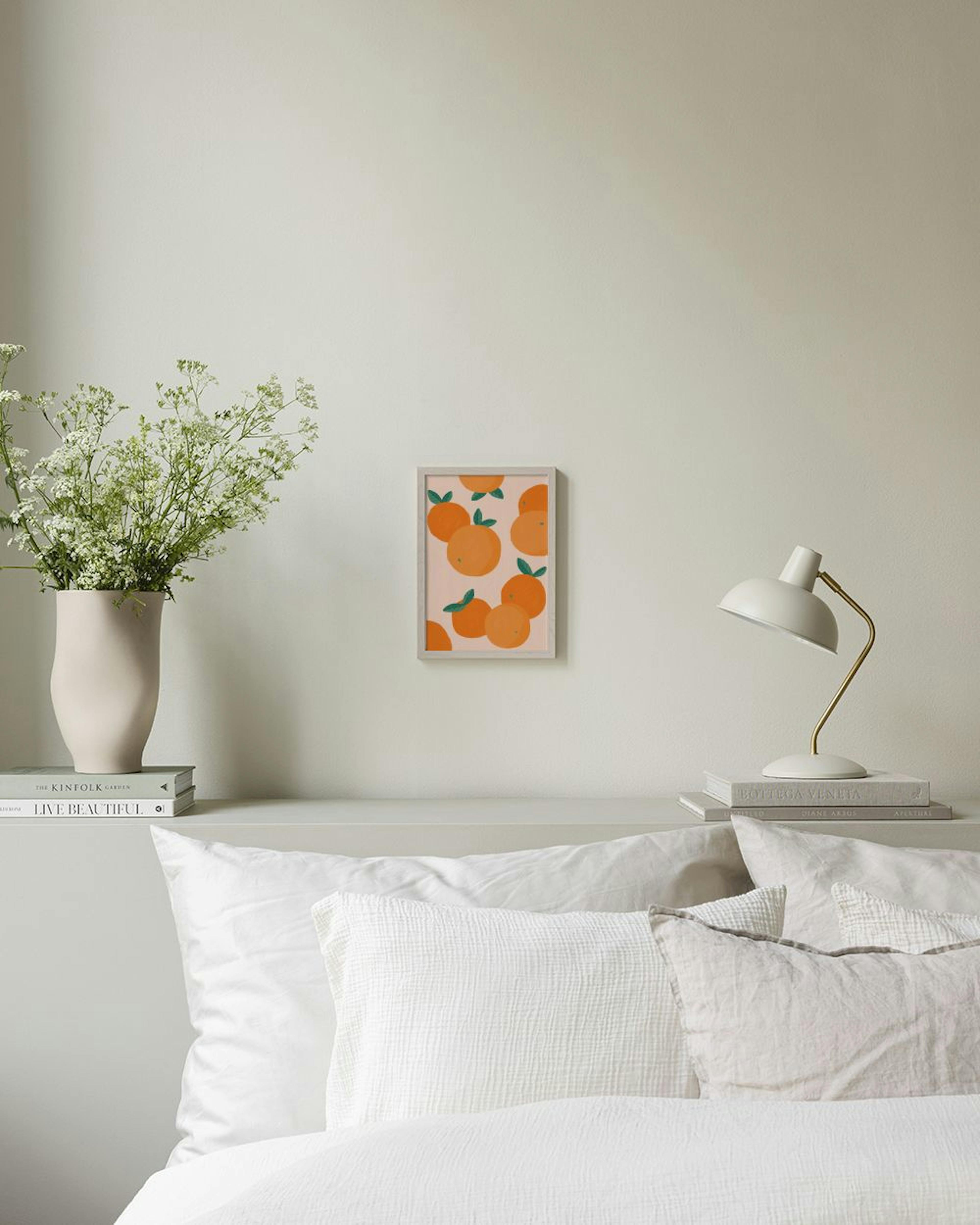 Affiche avec des oranges rondes et des feuilles vertes, suspendue sur un mur rose au-dessus dun meuble blanc.