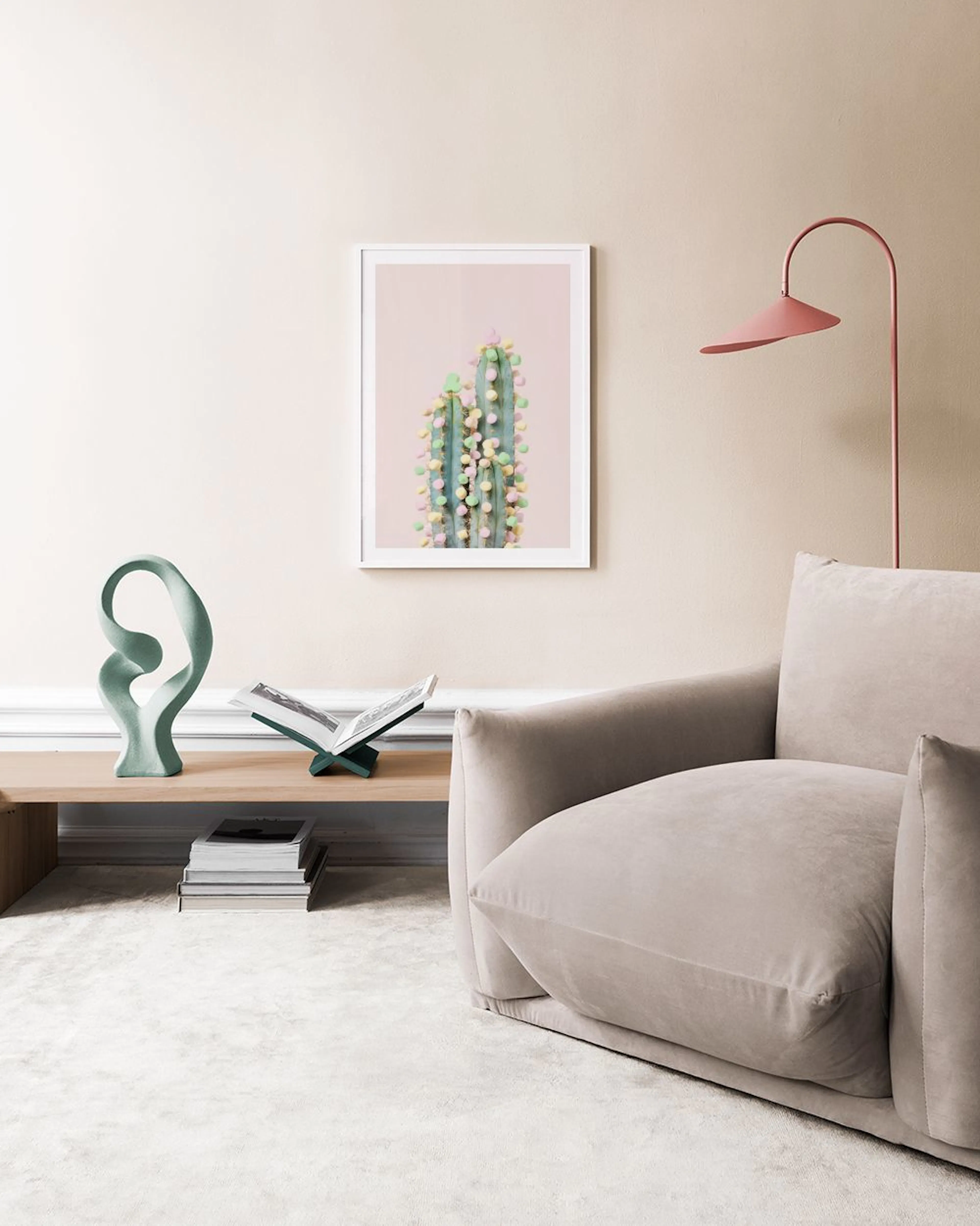 A decorative print of a cactus adorned with colorful pom-poms, displayed above a white dresser with vases and cups.