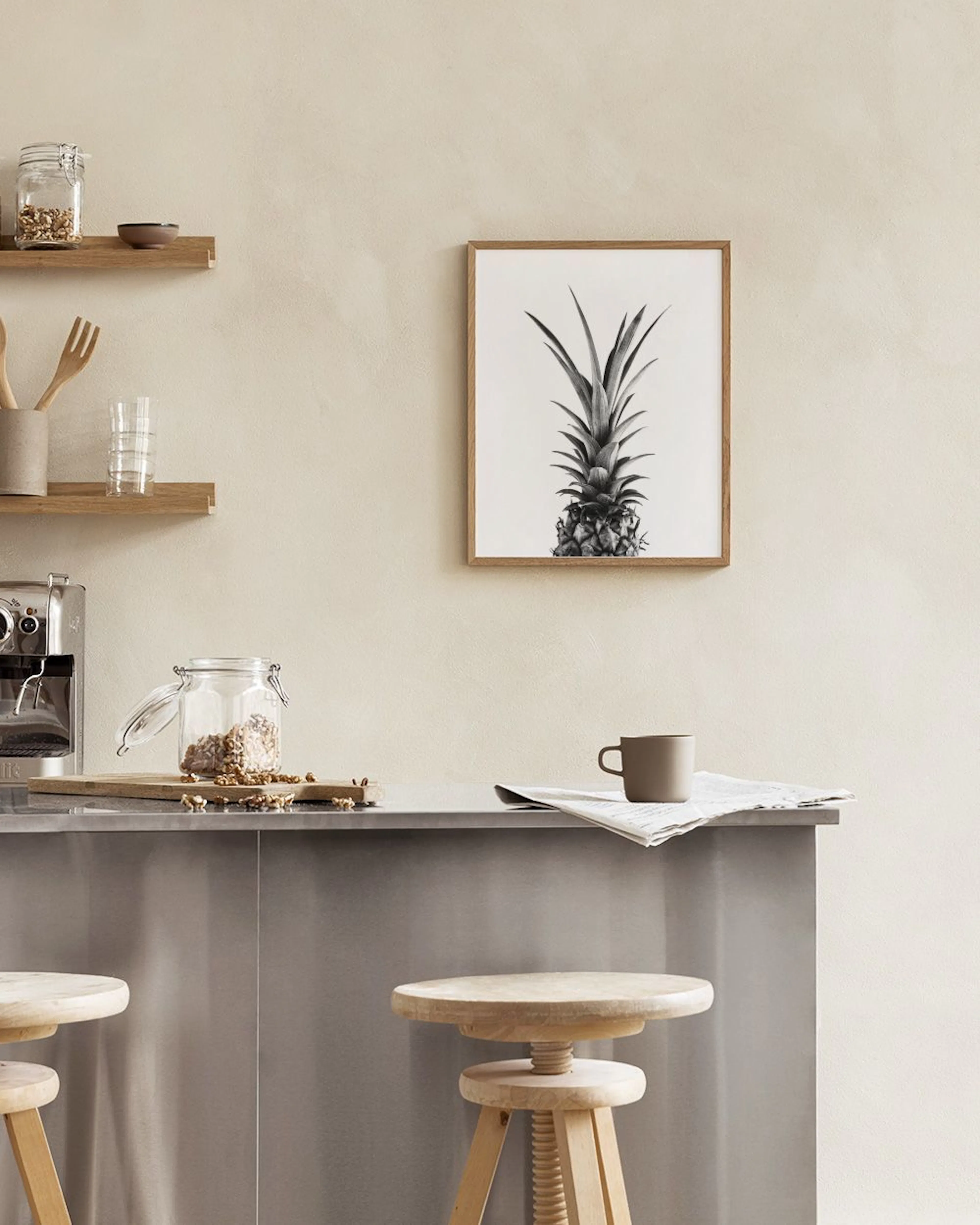 Affiche ananas noir et blanc, accrochée au-dessus dune table avec une chaise noire et un livre ouvert.