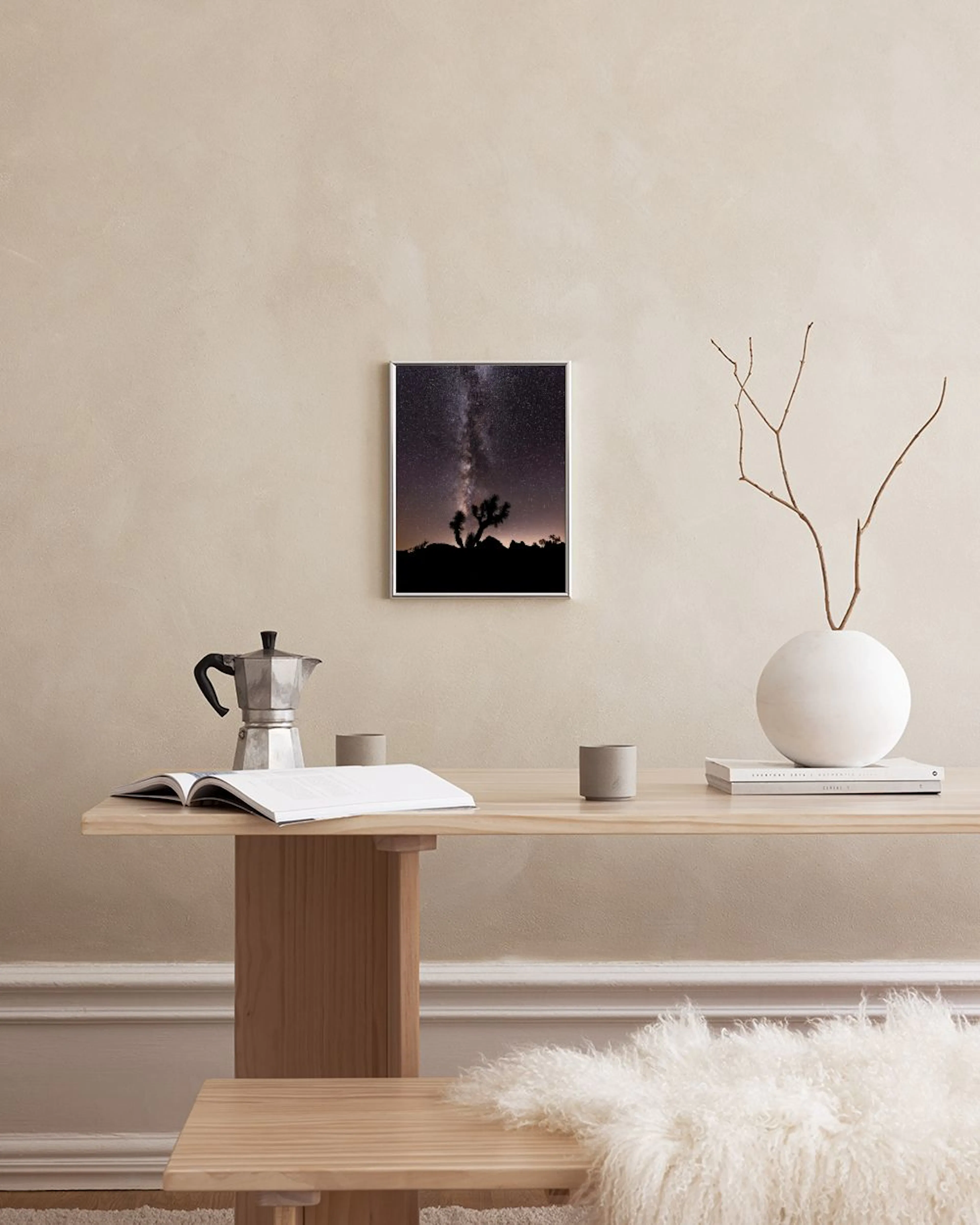 Poster eines Nachthimmels mit Milchstraße und Joshua Tree Silhouetten, über einem Schreibtisch in einem Zimmer.