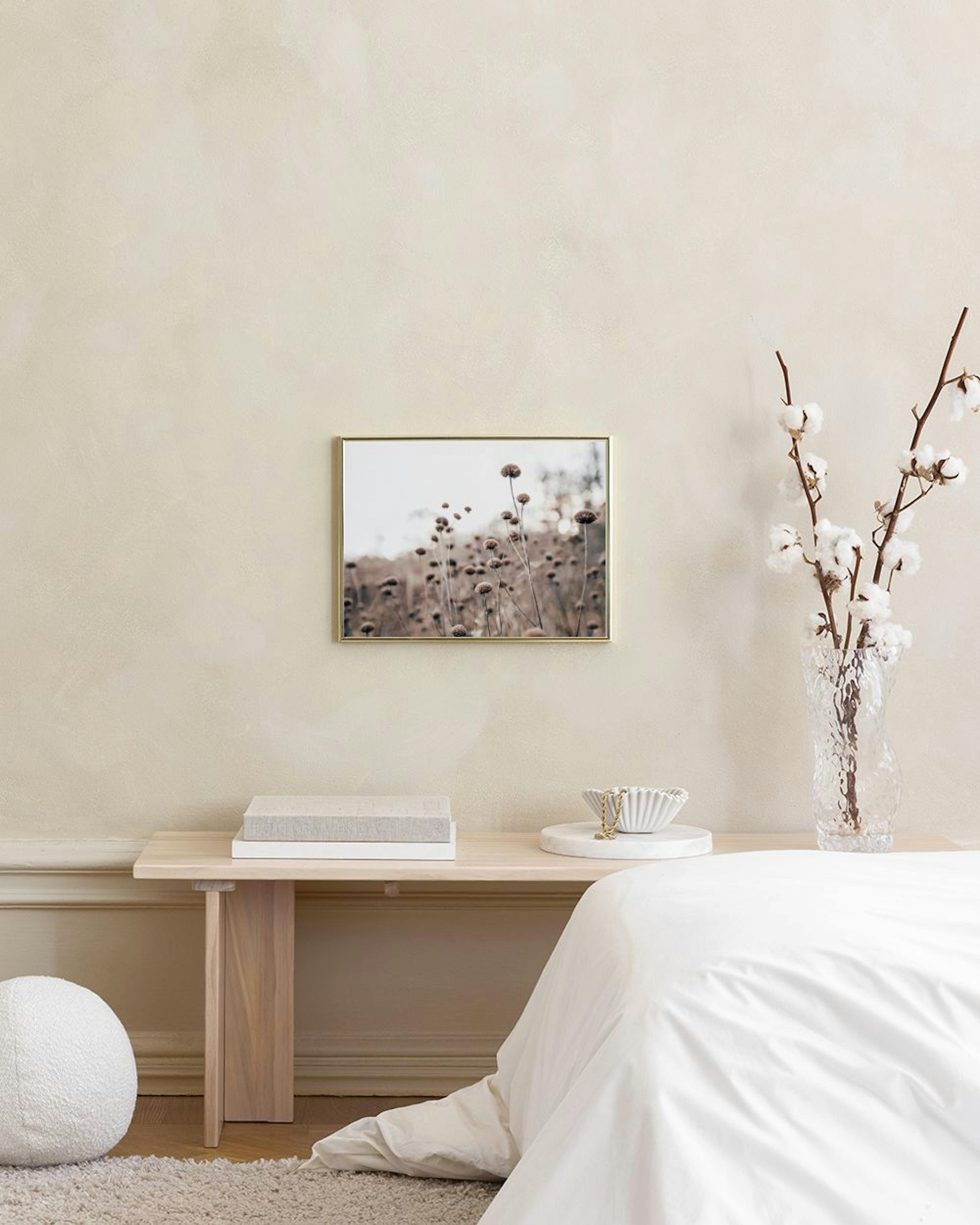 Affiche de fleurs séchées aux tons bruns et beiges, accrochée au-dessus de tables basses dorées dans un salon moderne.