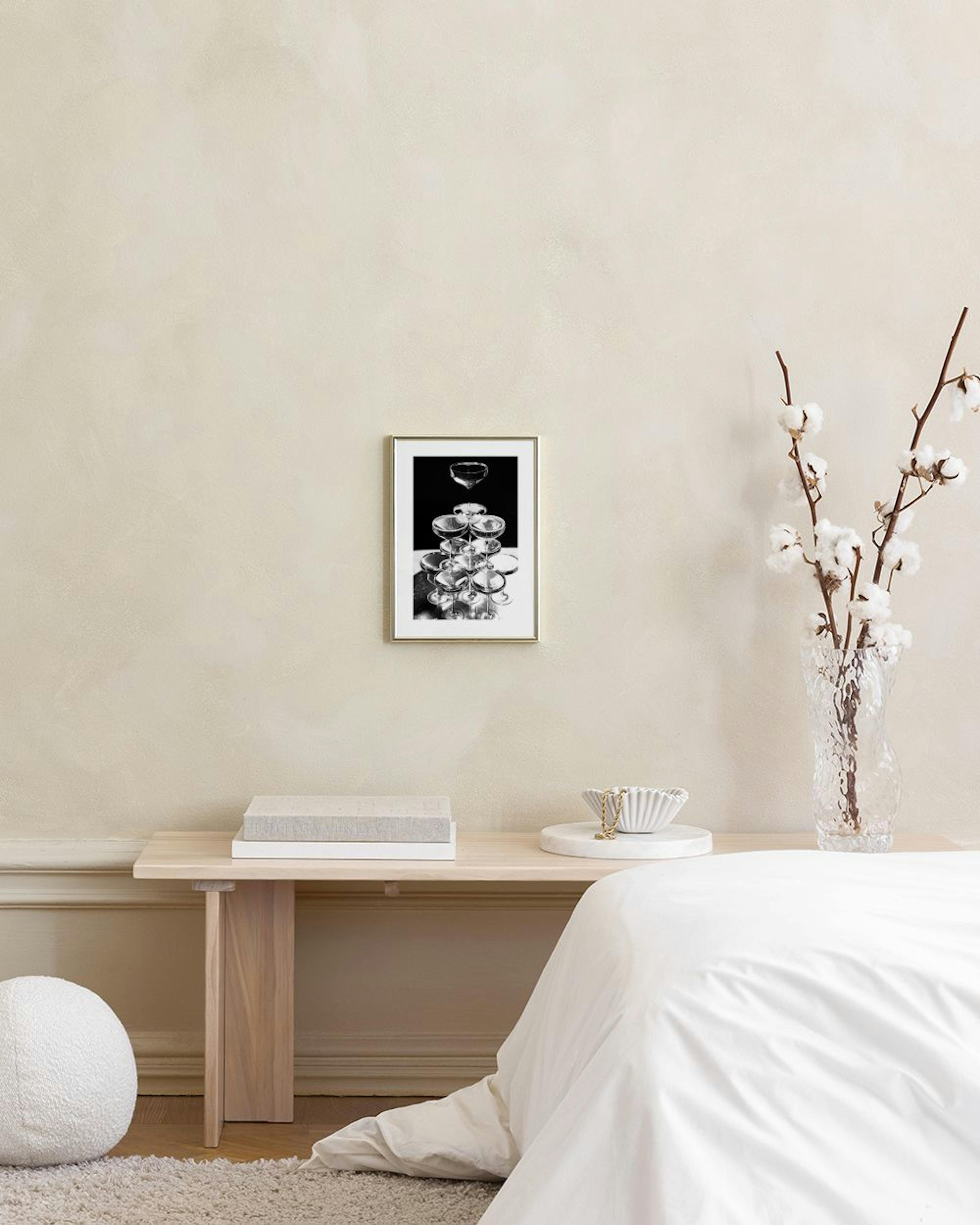 Poster med svartvitt fotografi av champagnetorn i ett rum med mörkgrön vägg, gardin och pall.