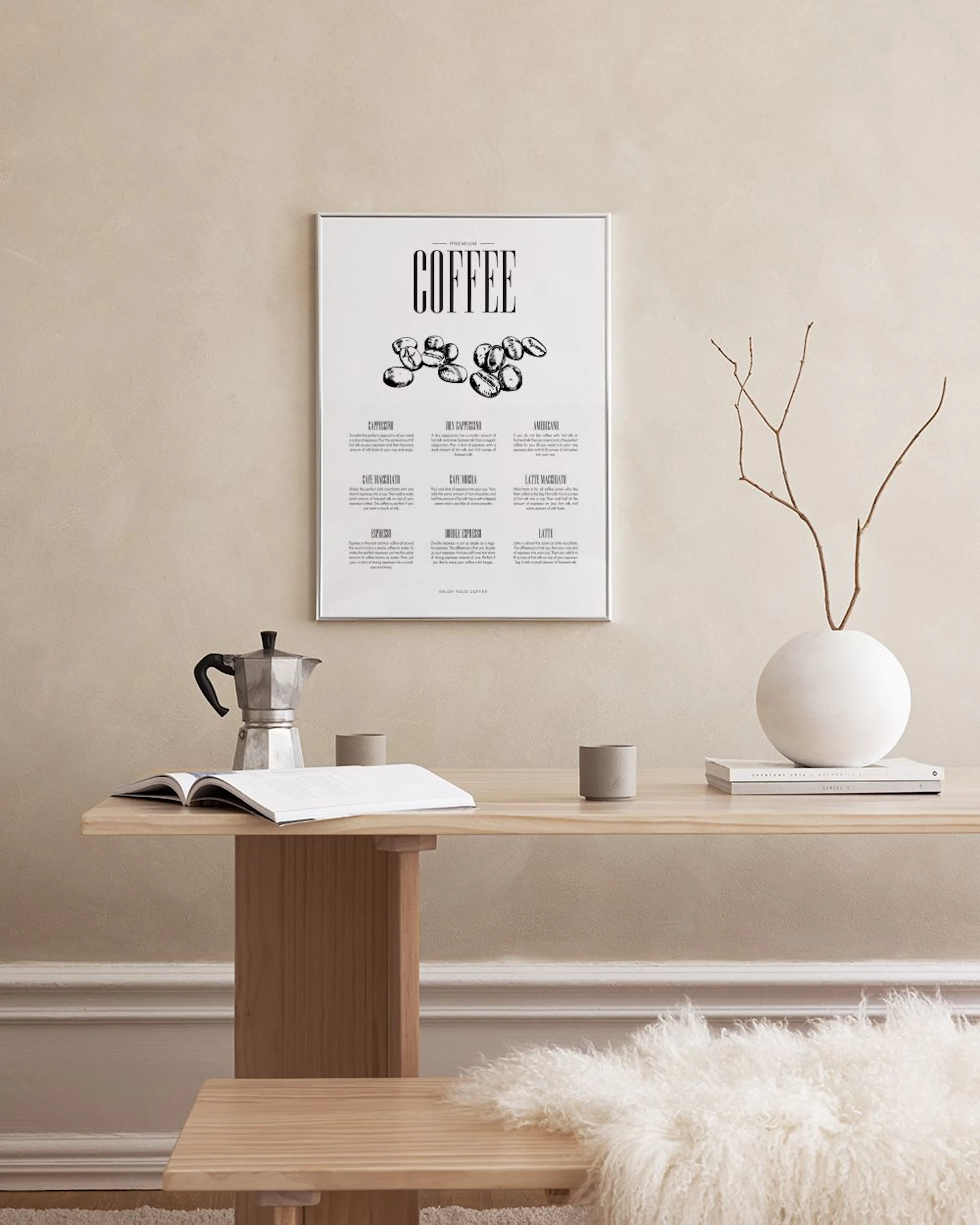 En kaffeposter med svarta kaffebönor och text i ett minimalistiskt kök med marmorvägg, bredvid en grön växt.