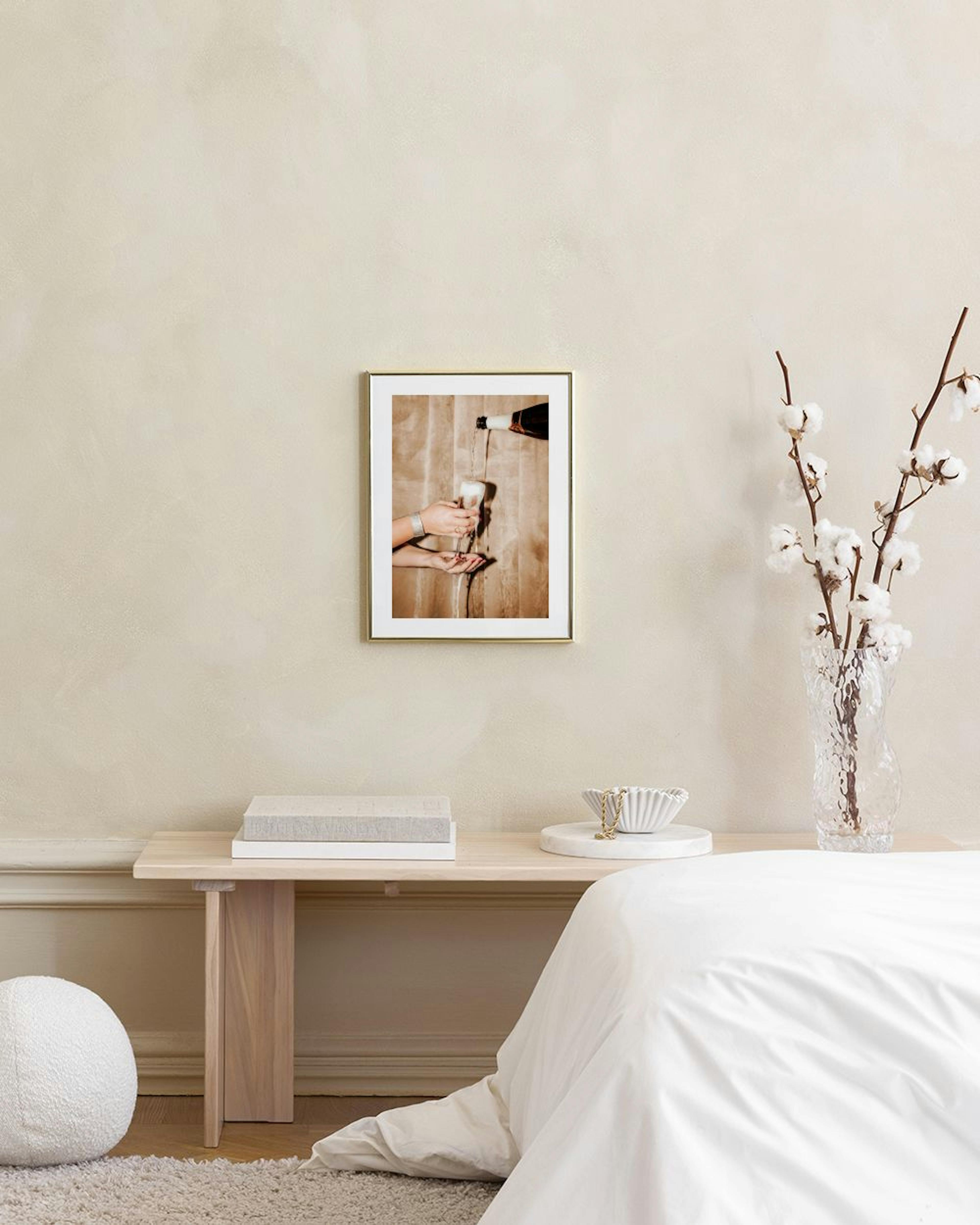 Affiche dune bouteille versant du champagne sur une main, accrochée au mur dun salon.
