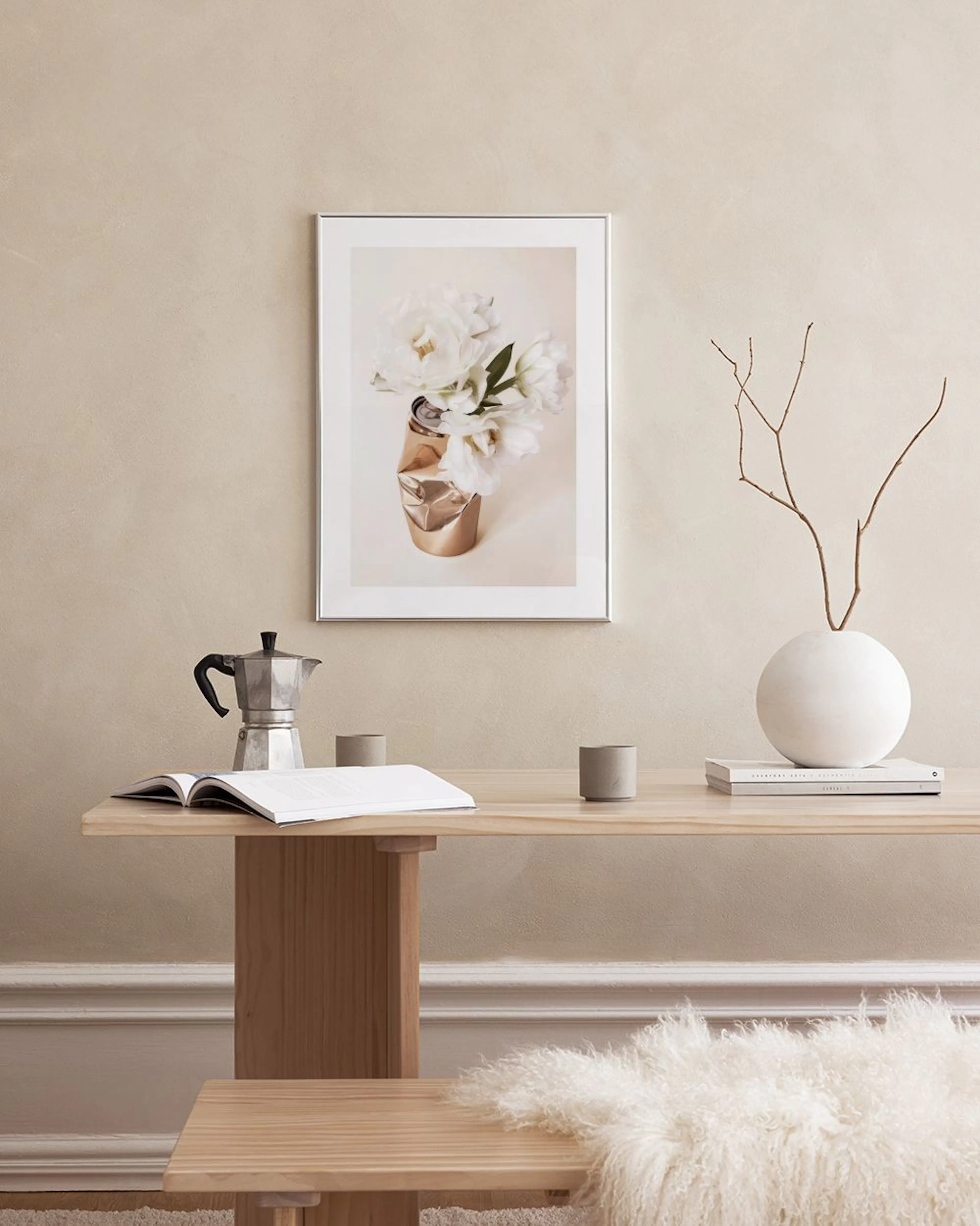 Poster av vita pioner i en guldskrynklad burk, hängande ovanför ett vitt marmorbord med vaser.