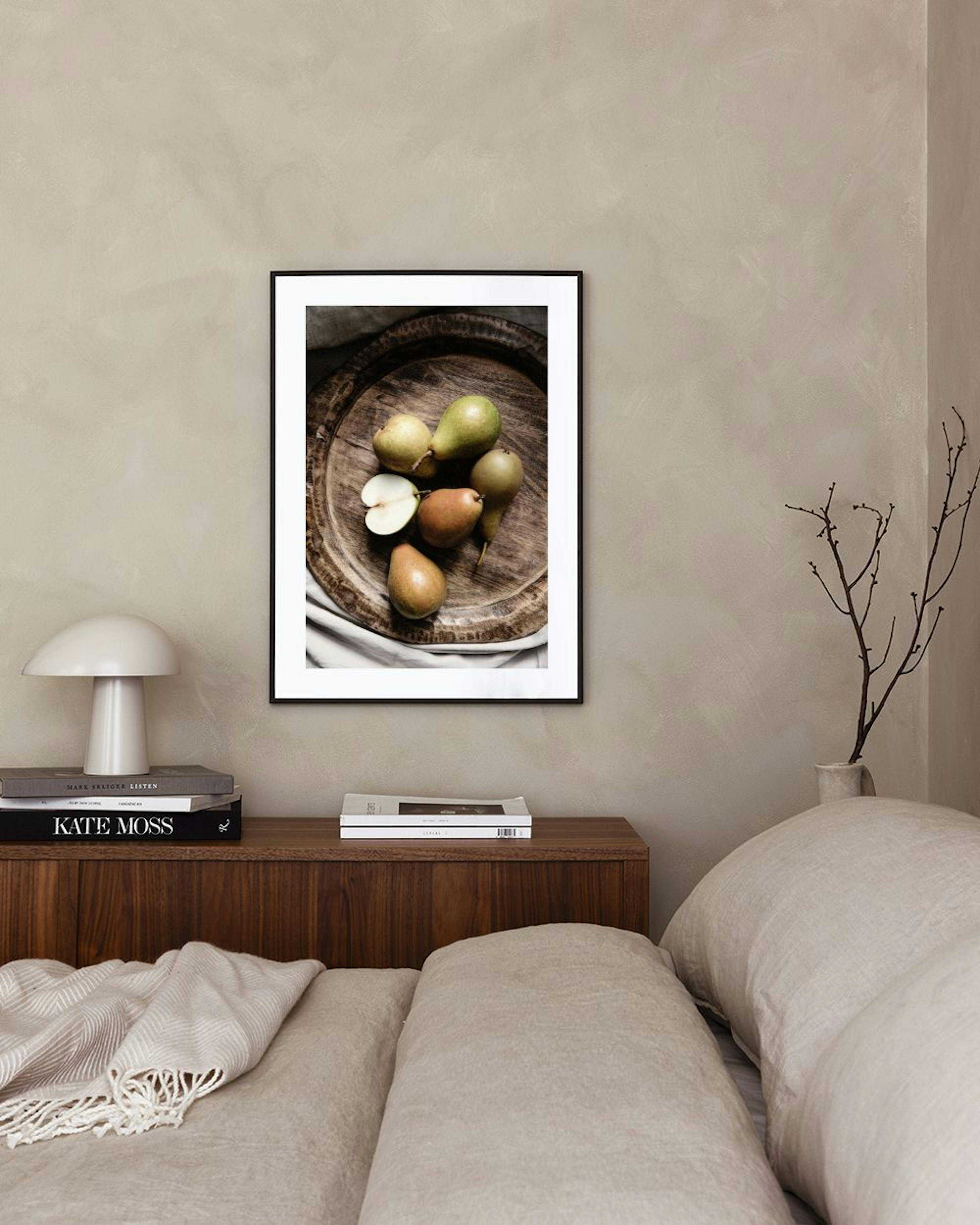 A print of assorted pears on a rustic wooden tray, hanging above a white marble side table with two vases and books.
