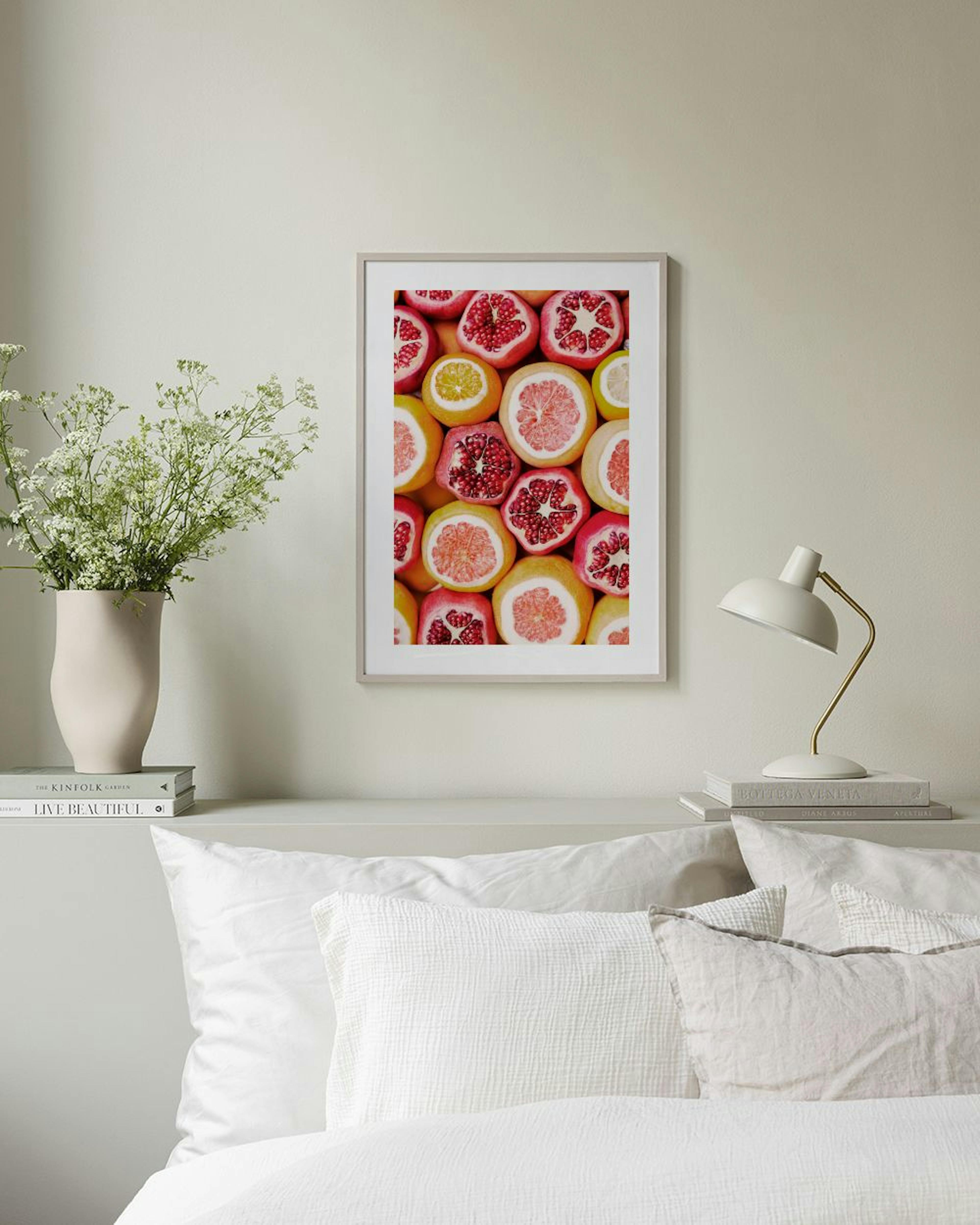 A print of sliced pomegranates, grapefruits, and lemons hanging above a white cabinet in a pink room.
