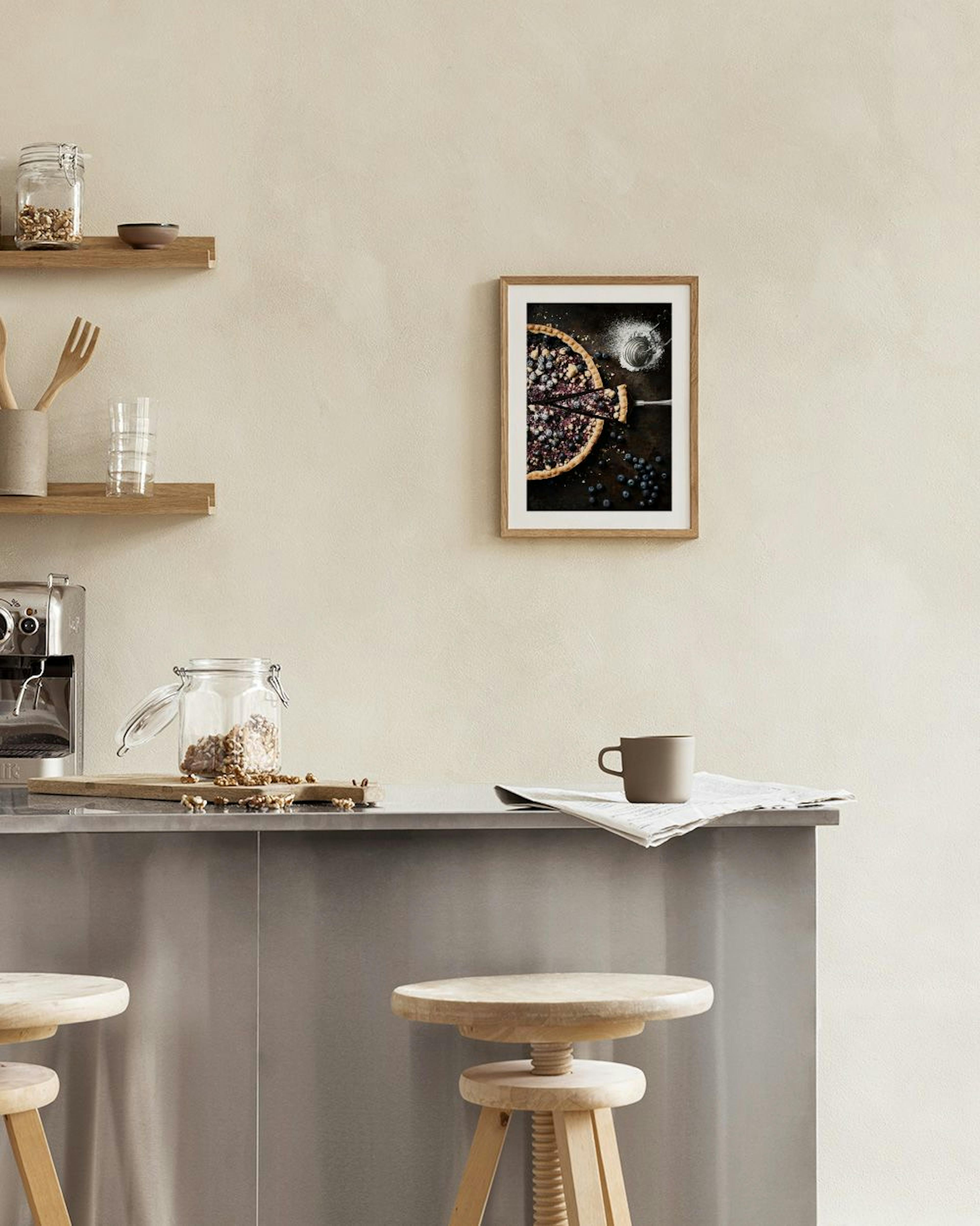 Poster van een bosbessentaart met poedersuiker op een donker oppervlak, hangend aan een witte muur boven een tafel met boek en s
