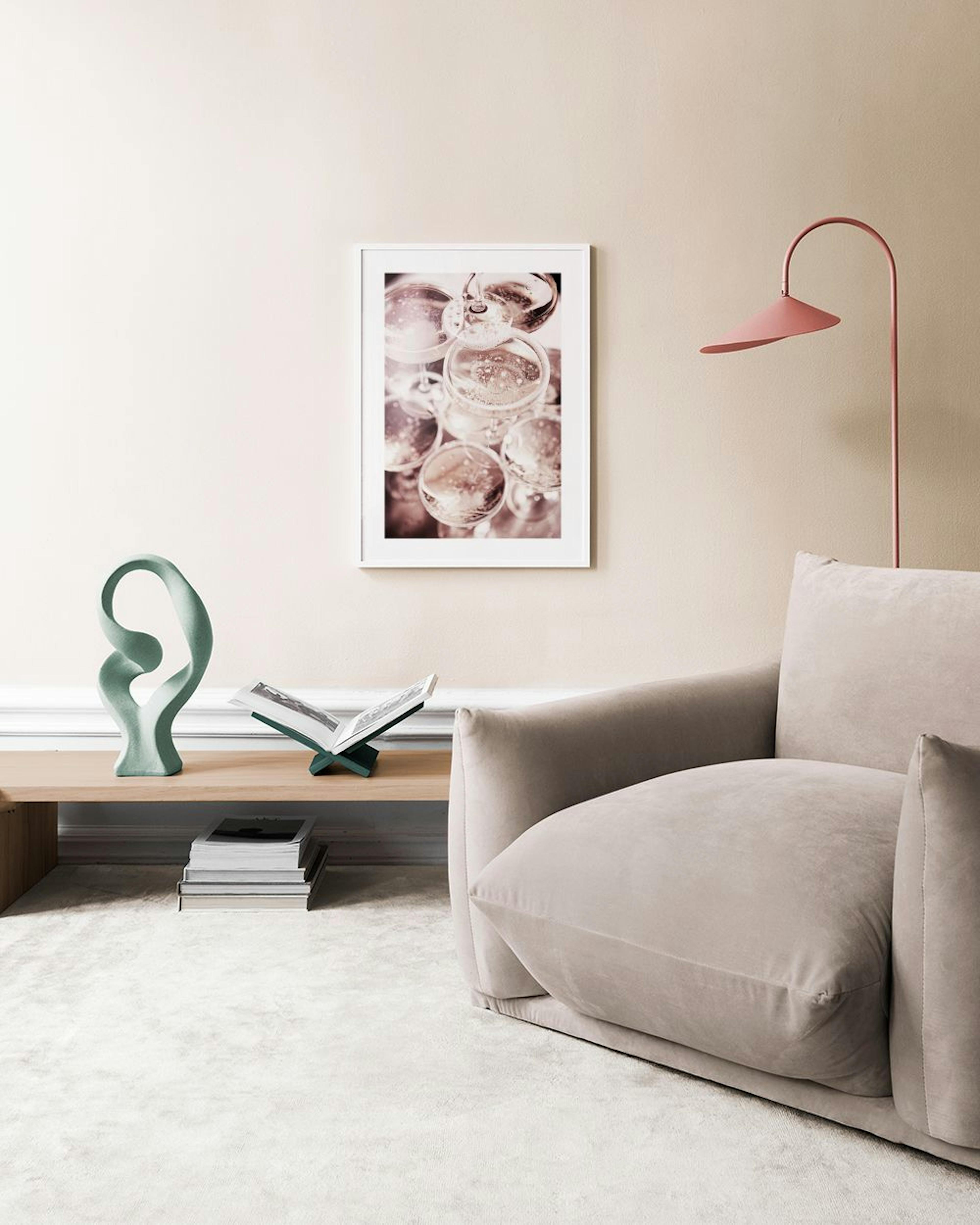 A print of champagne glasses with bubbles, hanging above a black round table with pink vases and a candle.