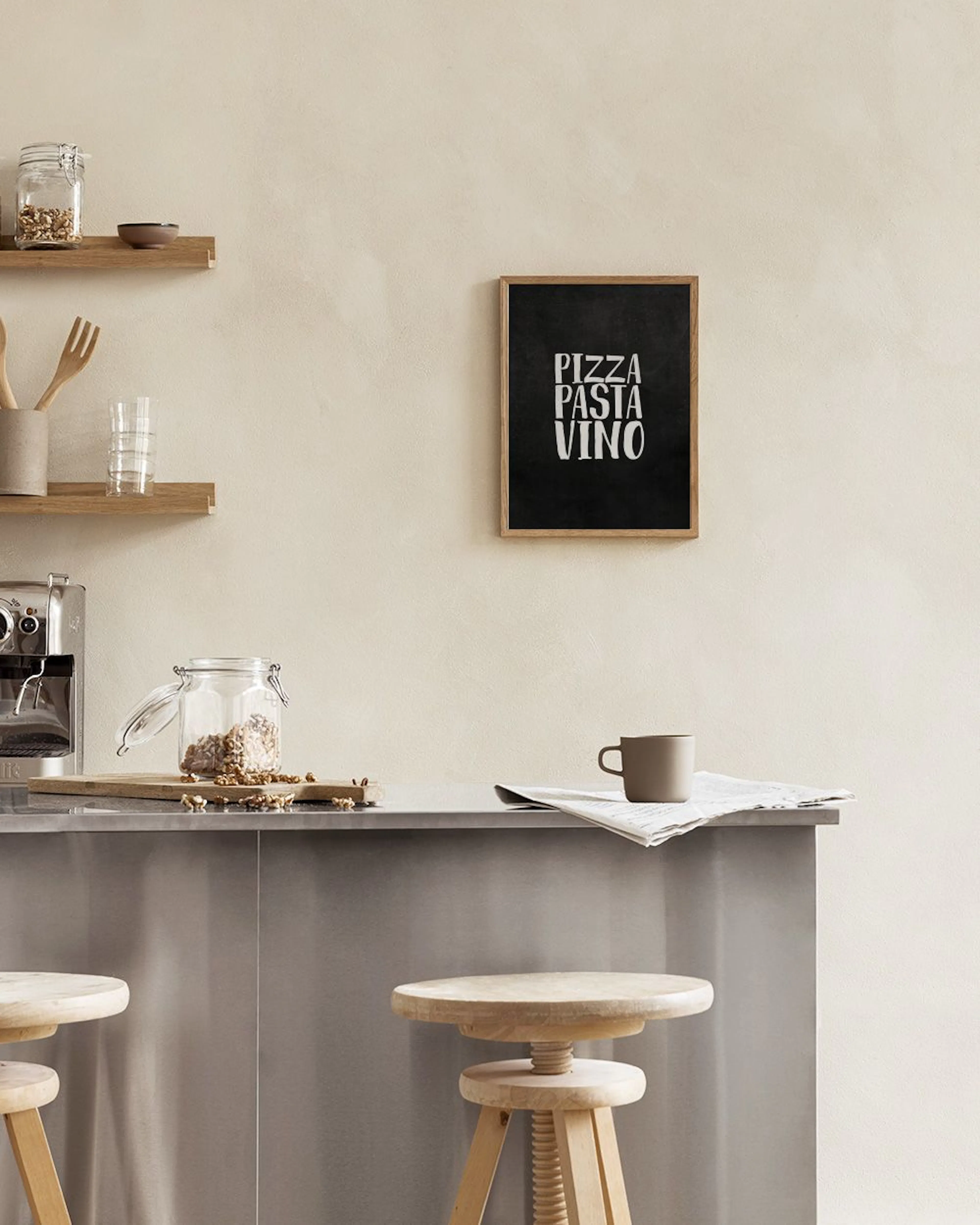 A black print with white text PIZZA PASTA VINO displayed on a white windowsill with books and a kettle.