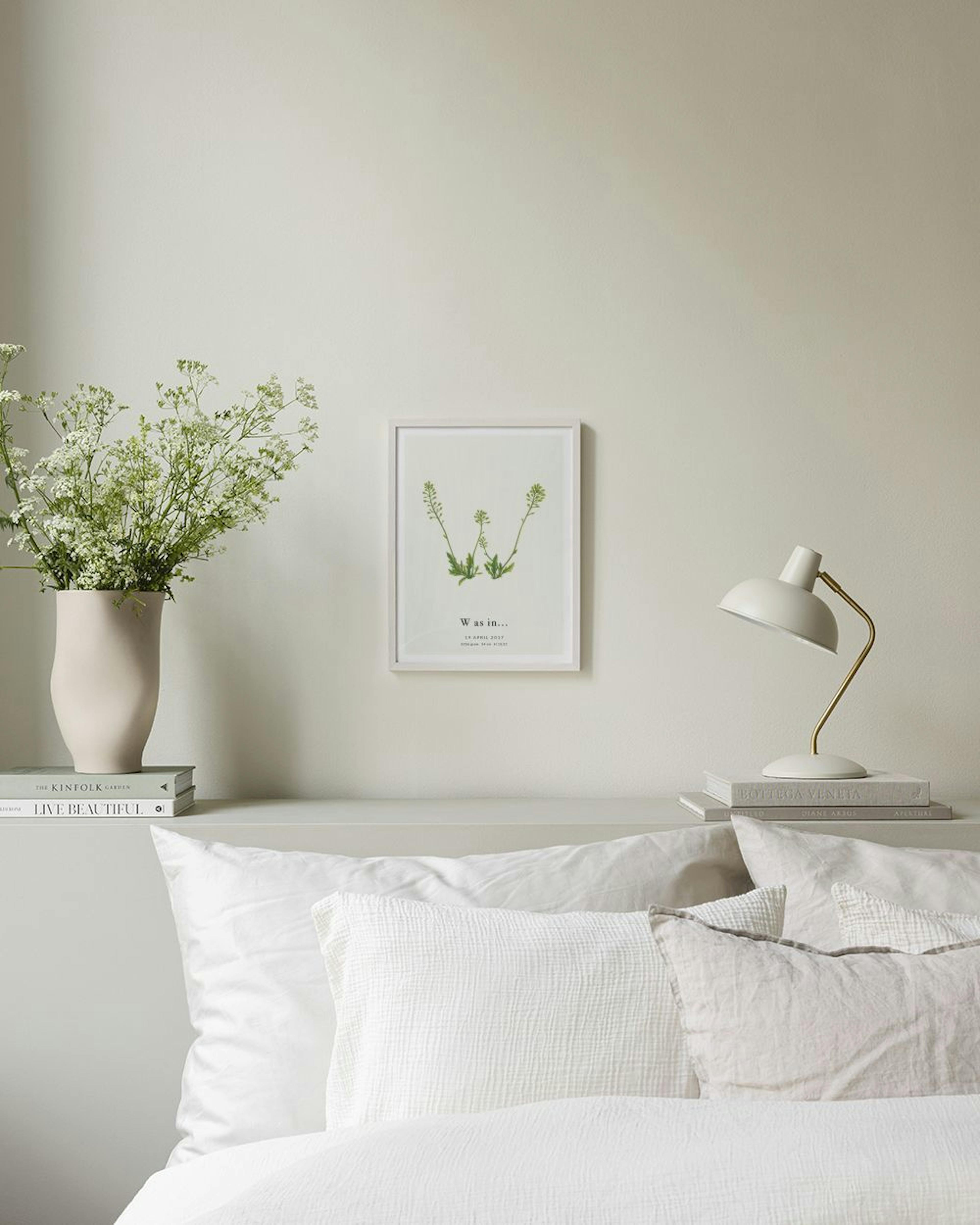 Personalised print with three green plant stems forming a W shape, hanging in a room with a black table, a grey sculpture, and a