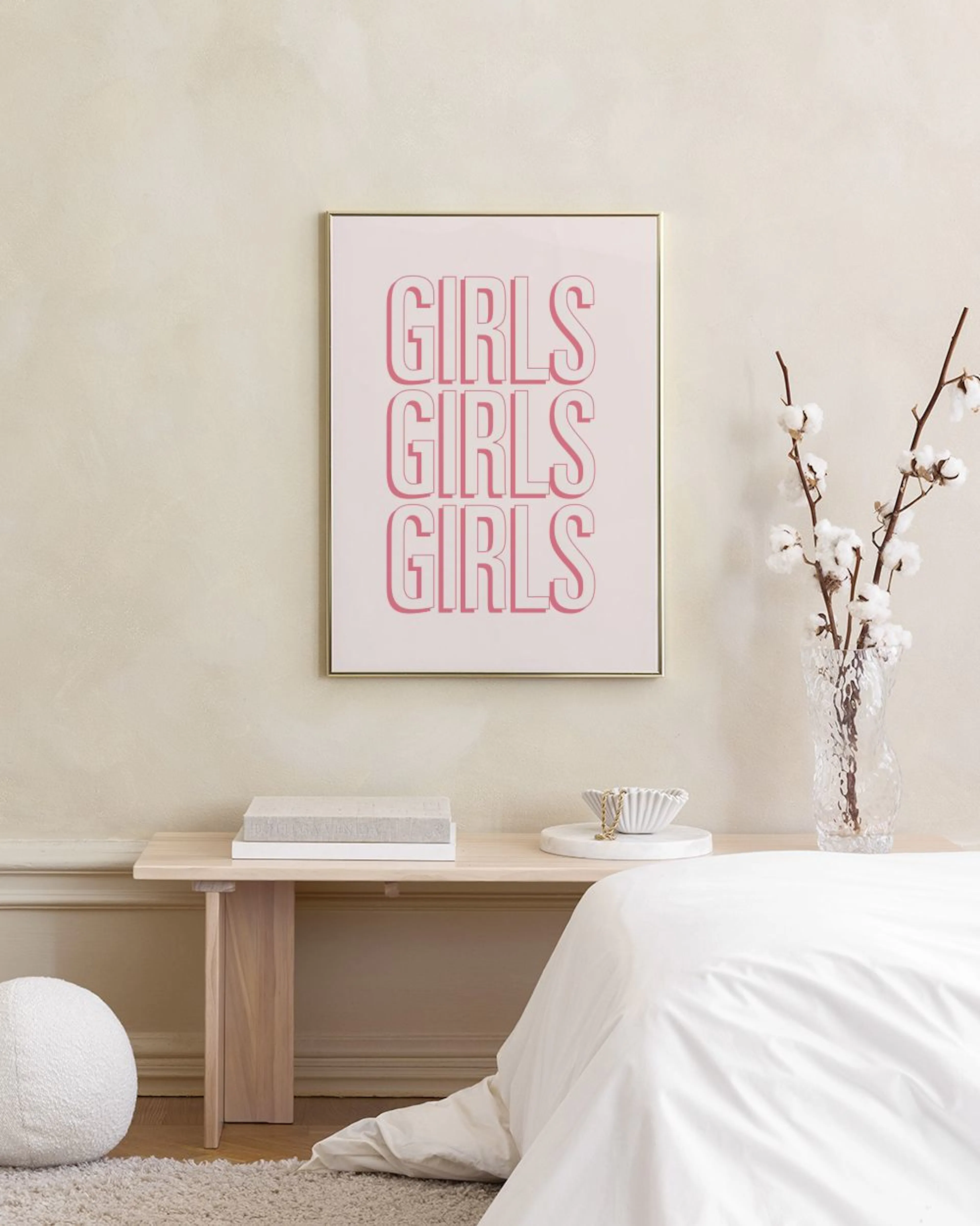 Poster mit dem Wort GIRLS dreimal in Rosa, auf einer weißen Kommode mit Blumen und Dekoration.