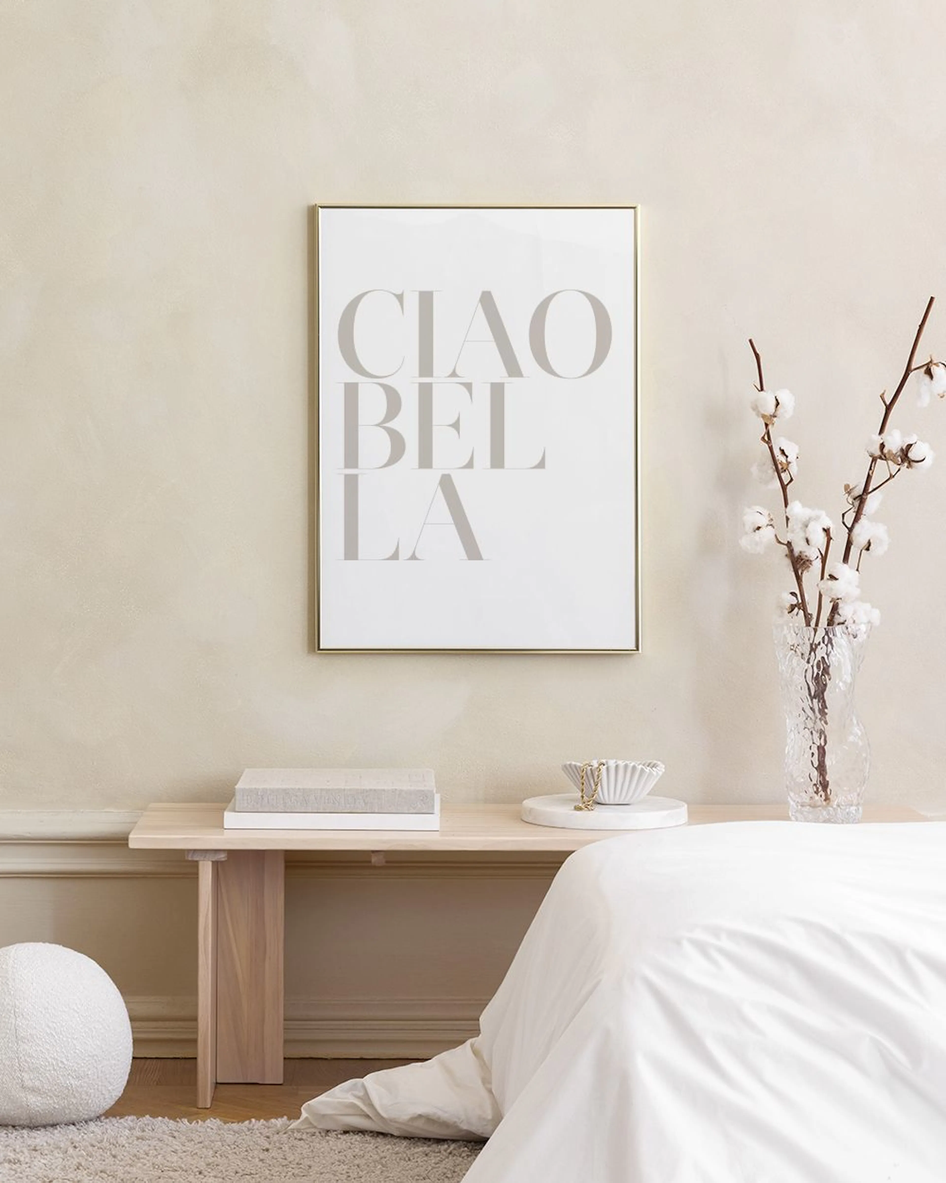 Poster met CIAO BELLA in grijsbruine letters, hangend boven een zwarte metalen console tafel met decoratie.