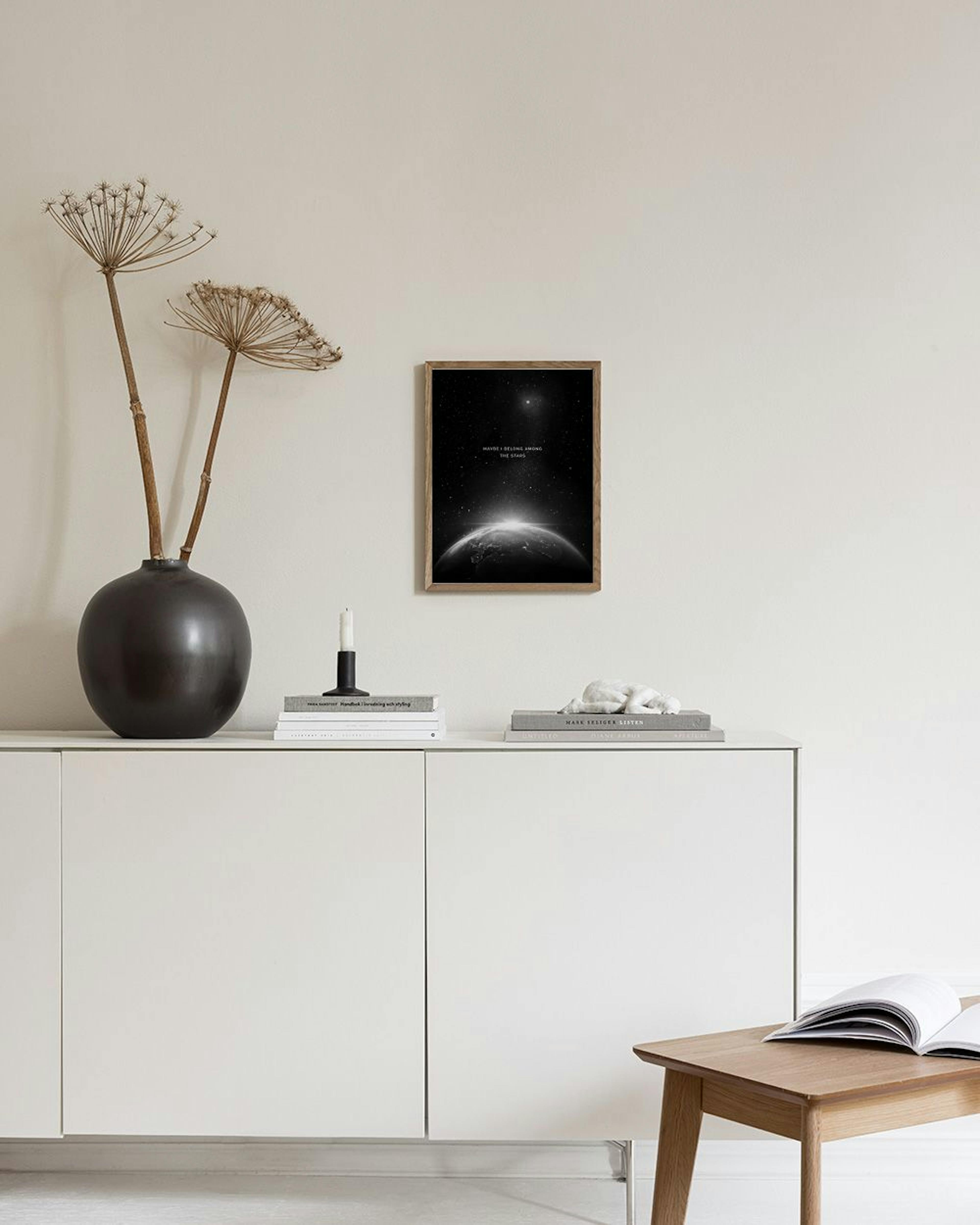Póster en blanco y negro con la Tierra y el amanecer espacial, colgado sobre un mueble blanco con una lámpara y libros.