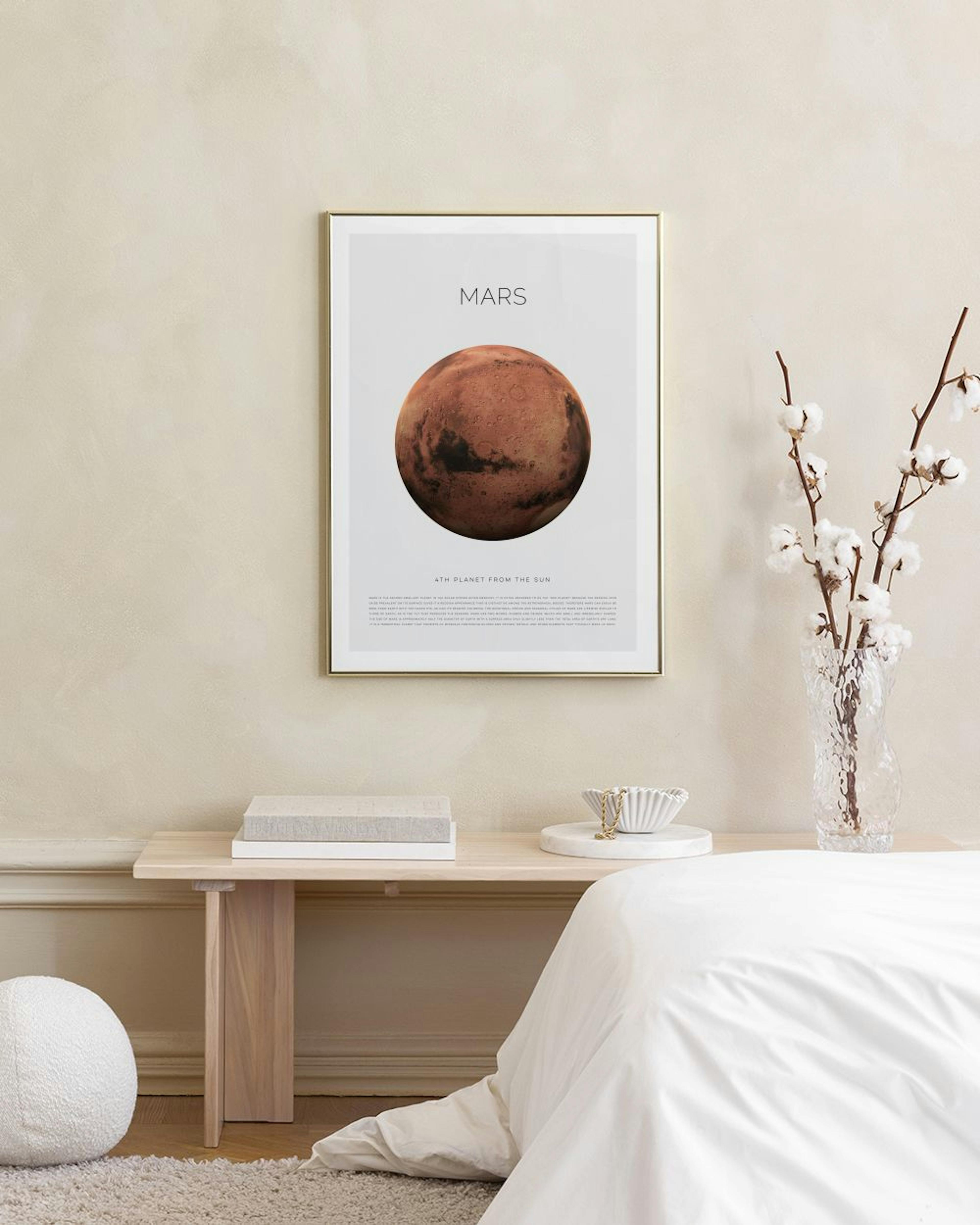 Póster del planeta Marte en tonos rojos y marrones, exhibido en una pared blanca sobre un taburete con libros.