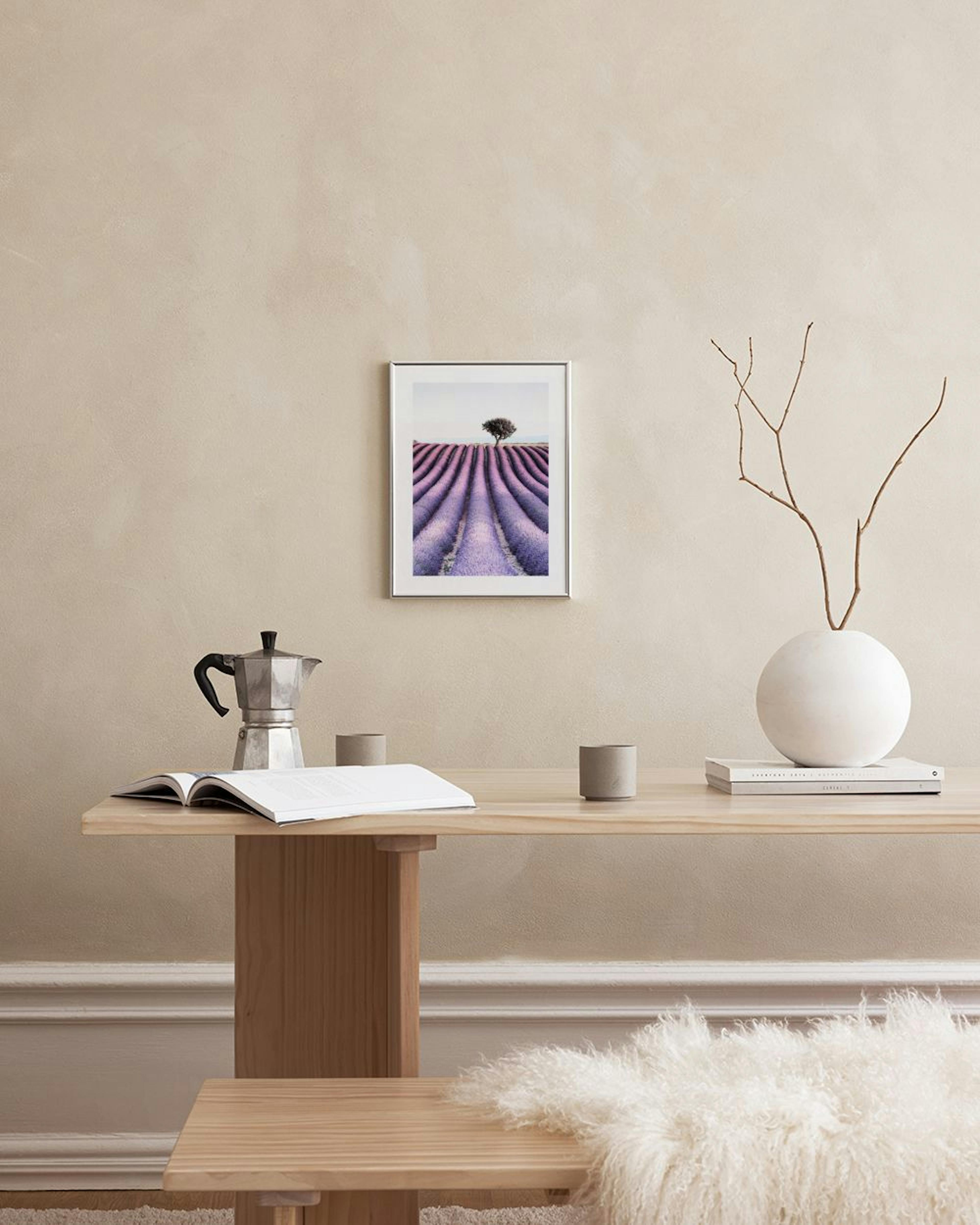 Poster eines Lavendelfeldes mit einem Baum am Horizont, hängt über einem Schreibtisch mit Stuhl, Büchern und Vase.