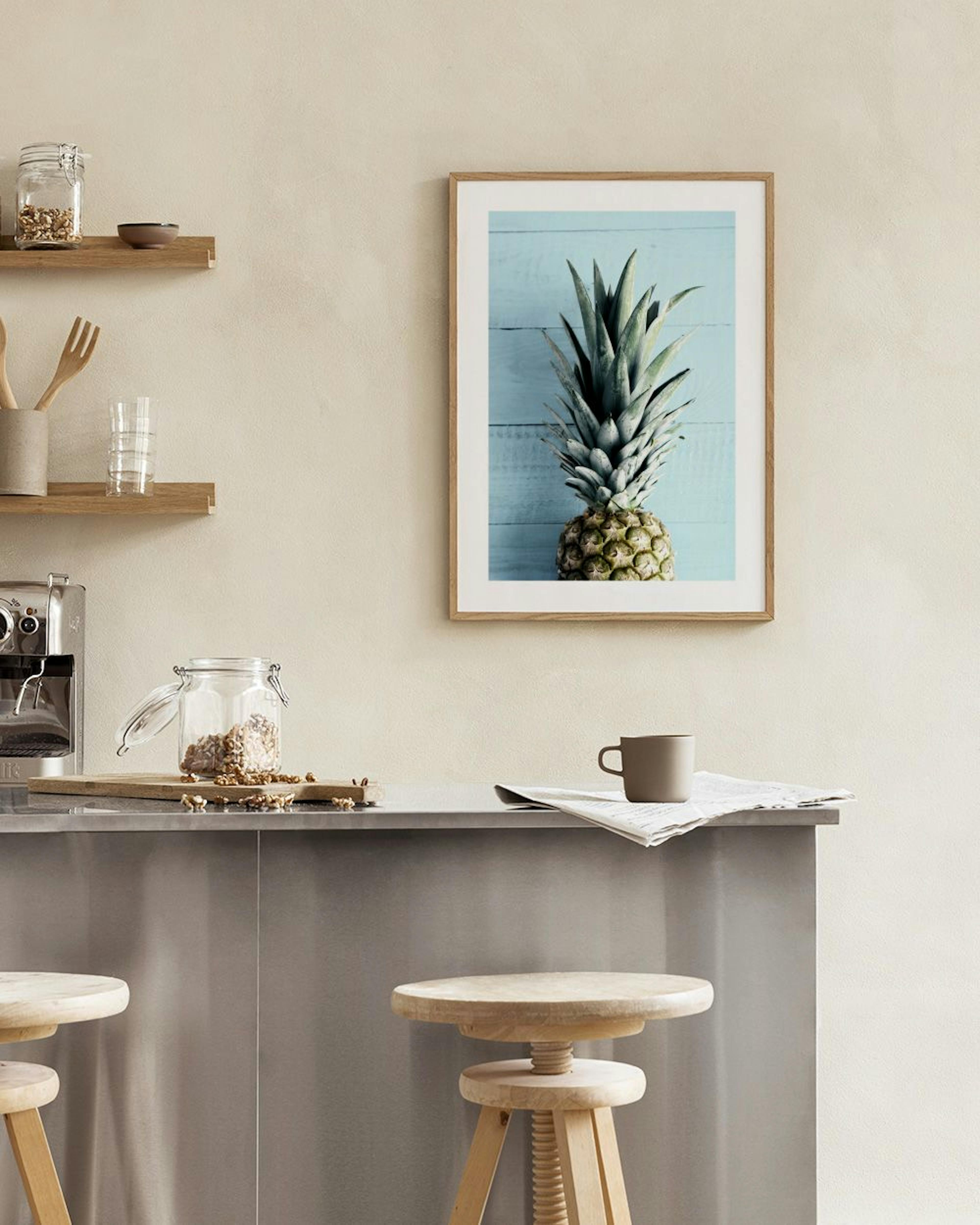Póster de una piña sobre un fondo azul claro de madera, colgado en una pared blanca sobre una mesa de comedor.