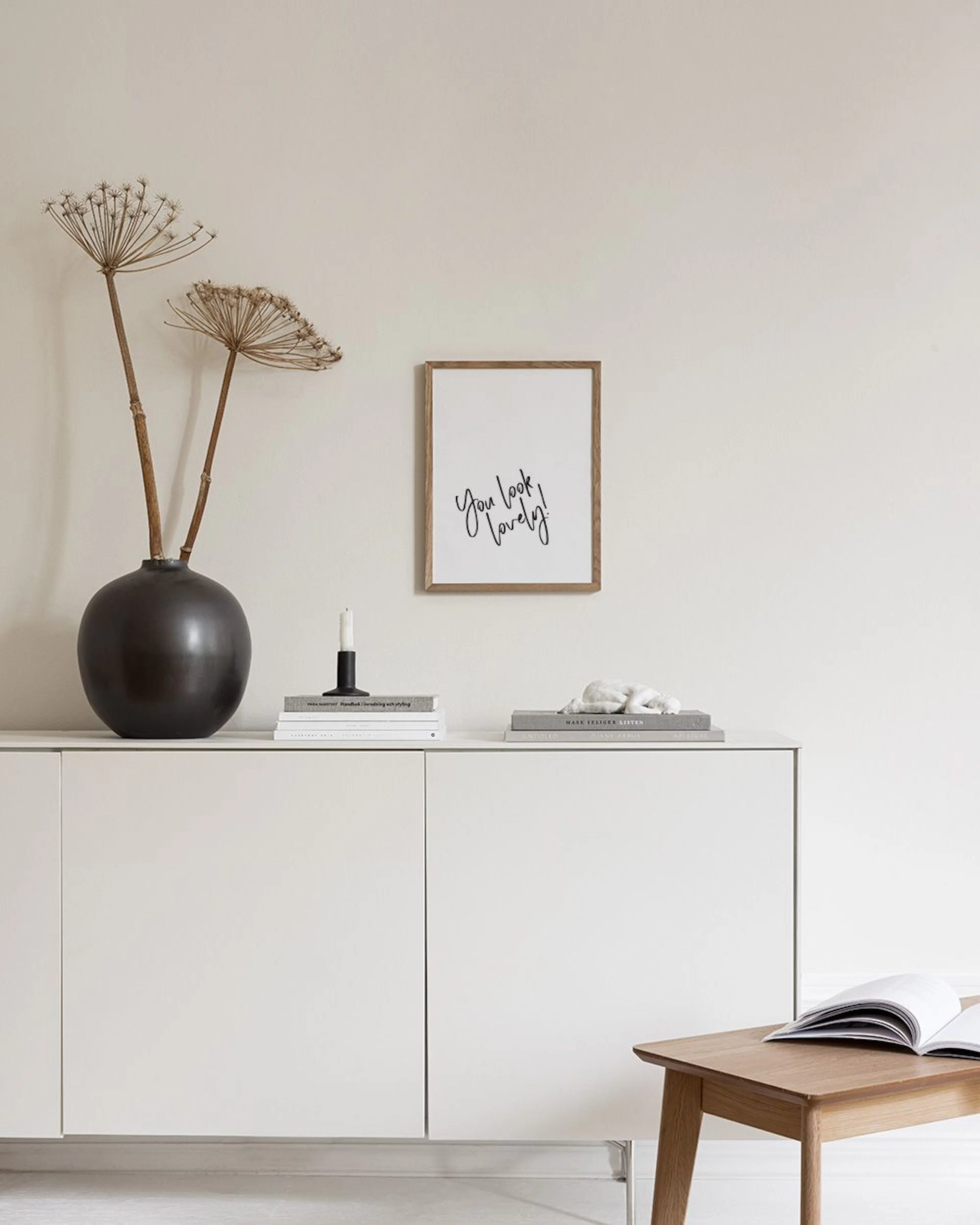 Poster med texten You look lovely! i svart handskriven stil, visad på en svart hylla med böcker och timglas.