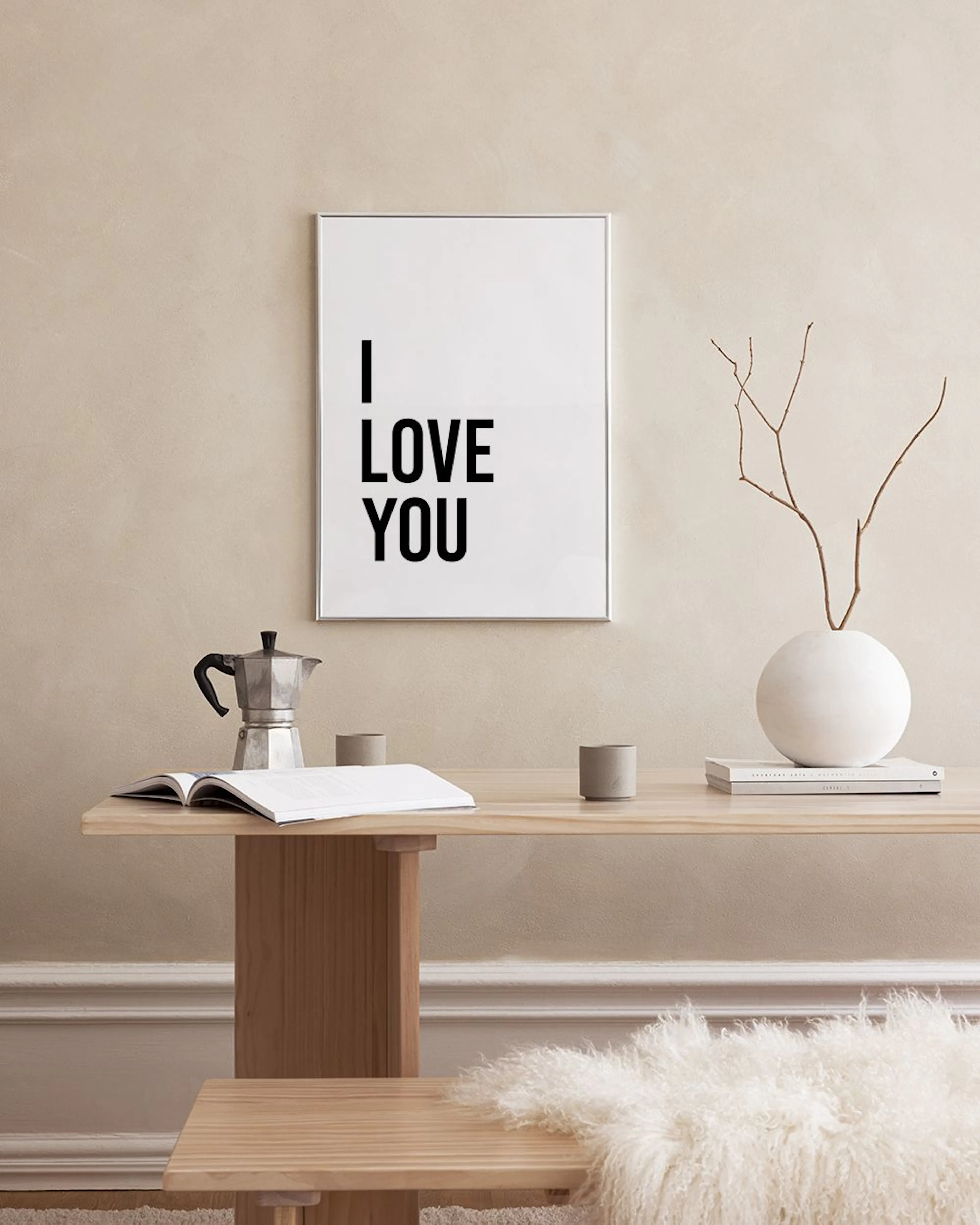 Affiche murale blanche avec le texte noir I LOVE YOU en majuscules, suspendue au-dessus dun meuble bleu marine. Des vases bleus 