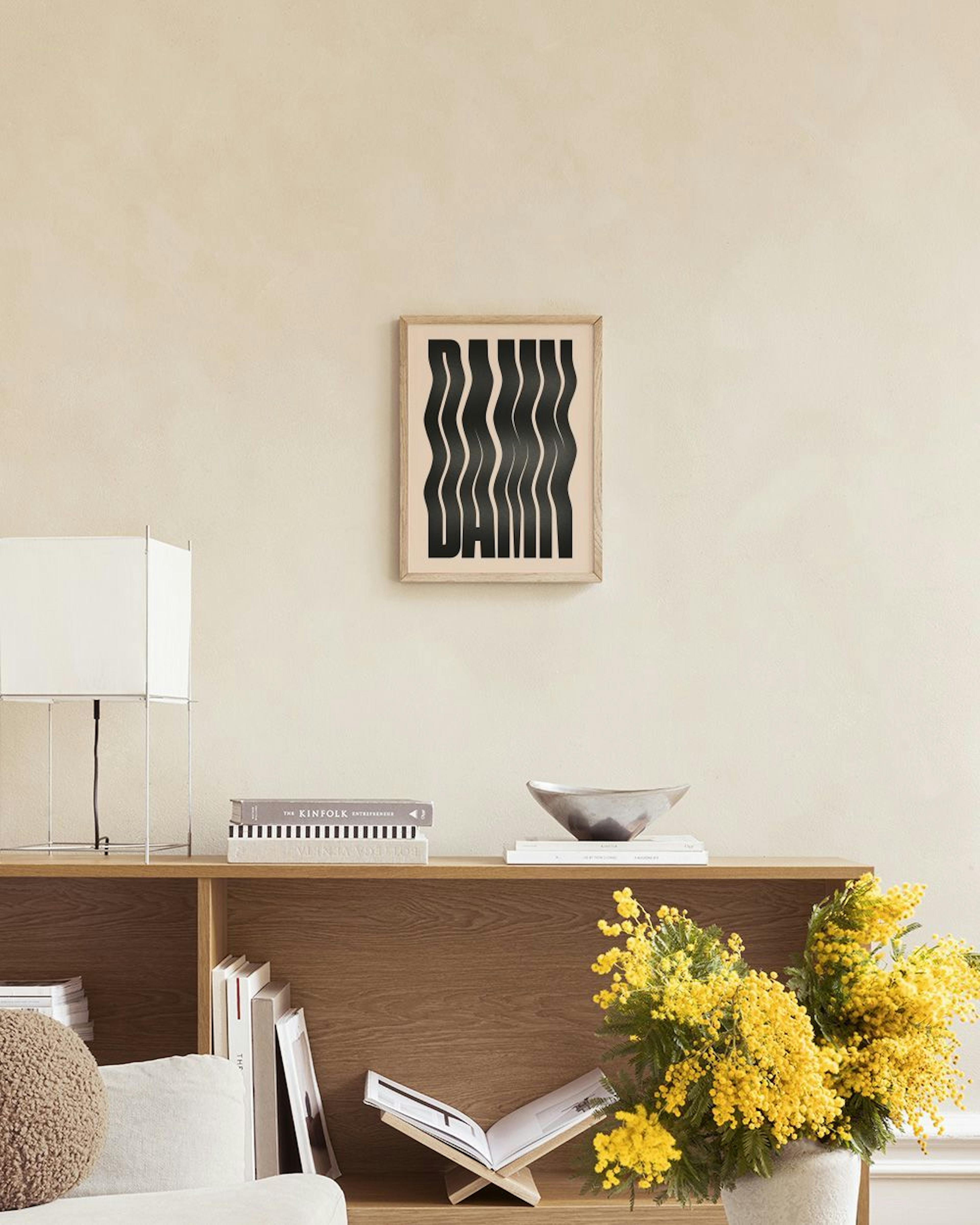 A print of the word DAMN in black wavy letters on a beige background, hanging above a white marble table with vases and books.