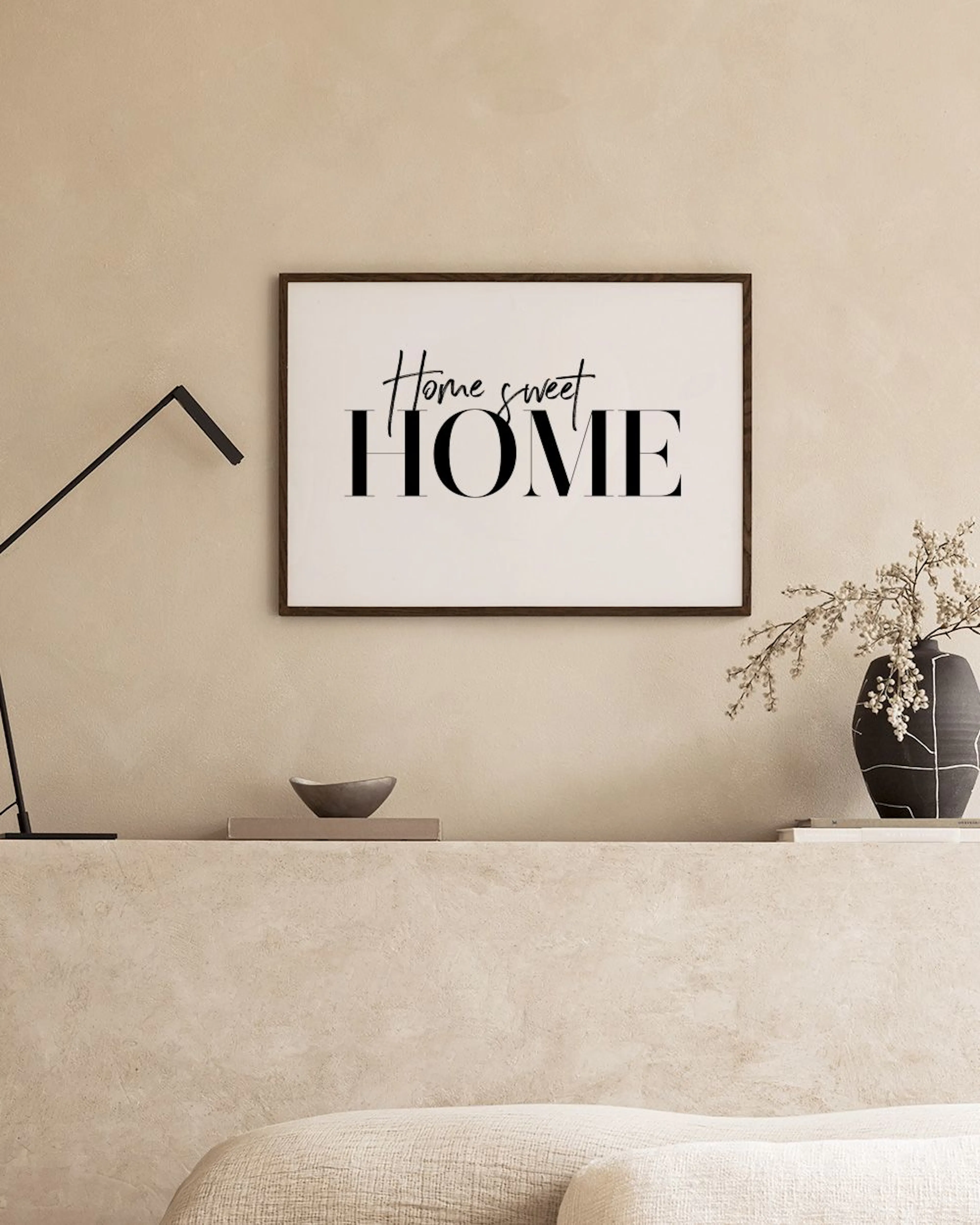A print with Home sweet HOME in black script and block letters, displayed above a black console table in a modern living room.