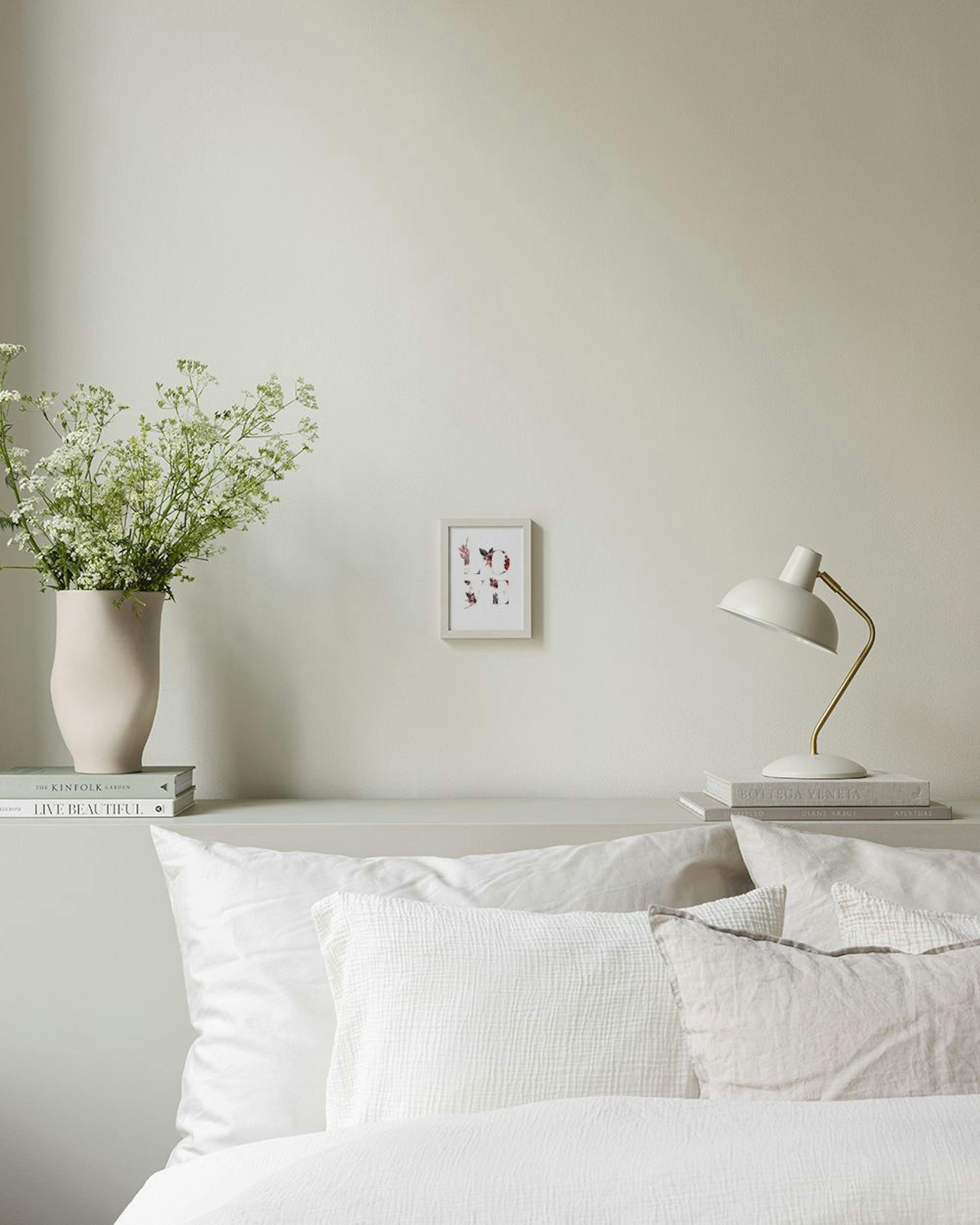 Poster met het woord LOVE gevormd door bloemmotieven, hangend boven een salontafel in een moderne woonkamer.