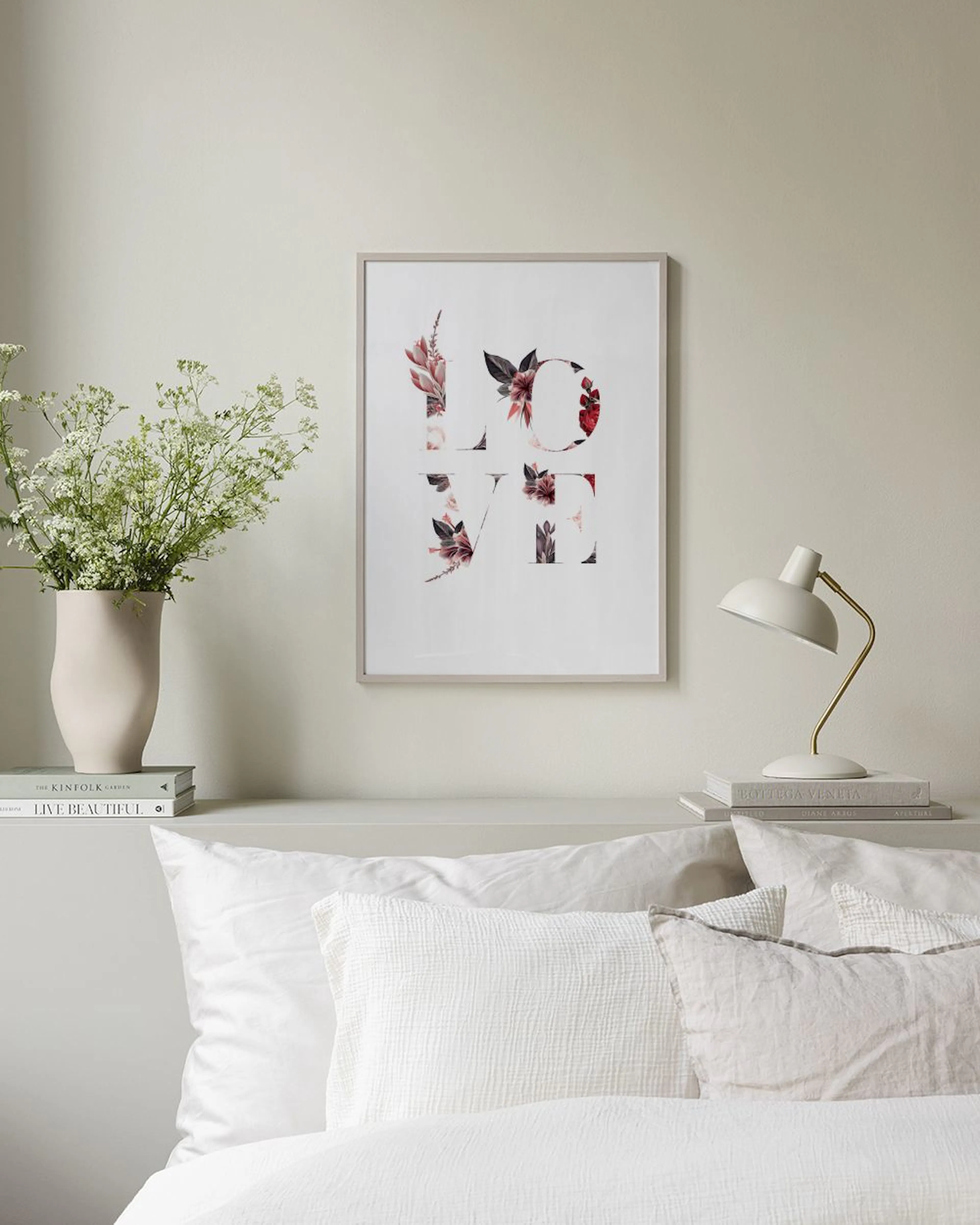 A love print with dark red and pink floral elements, hanging in a modern living room above a black coffee table.