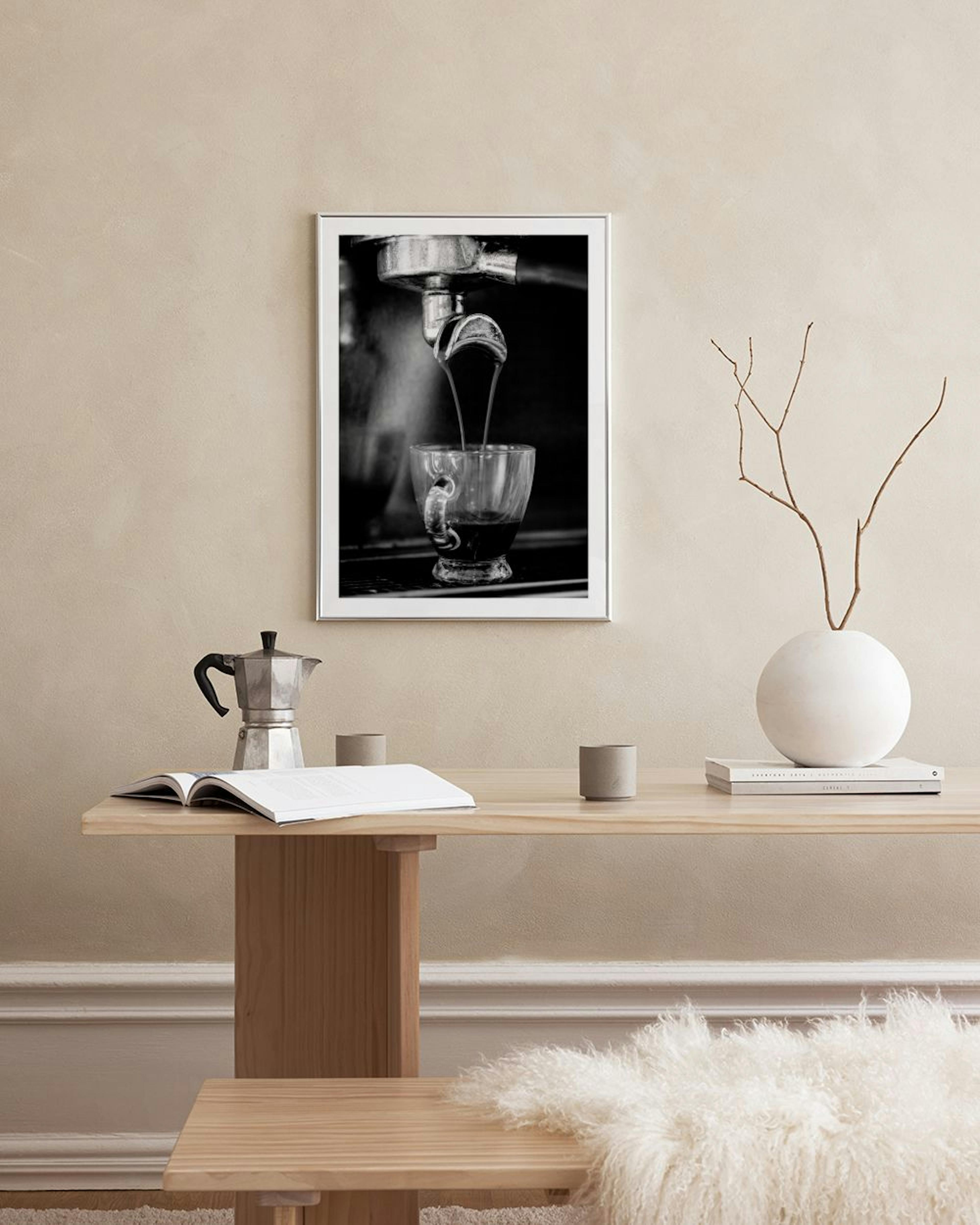 Póster monocromático de una cafetera espresso sirviendo café en una taza, exhibido sobre una mesa de comedor con un libro abiert