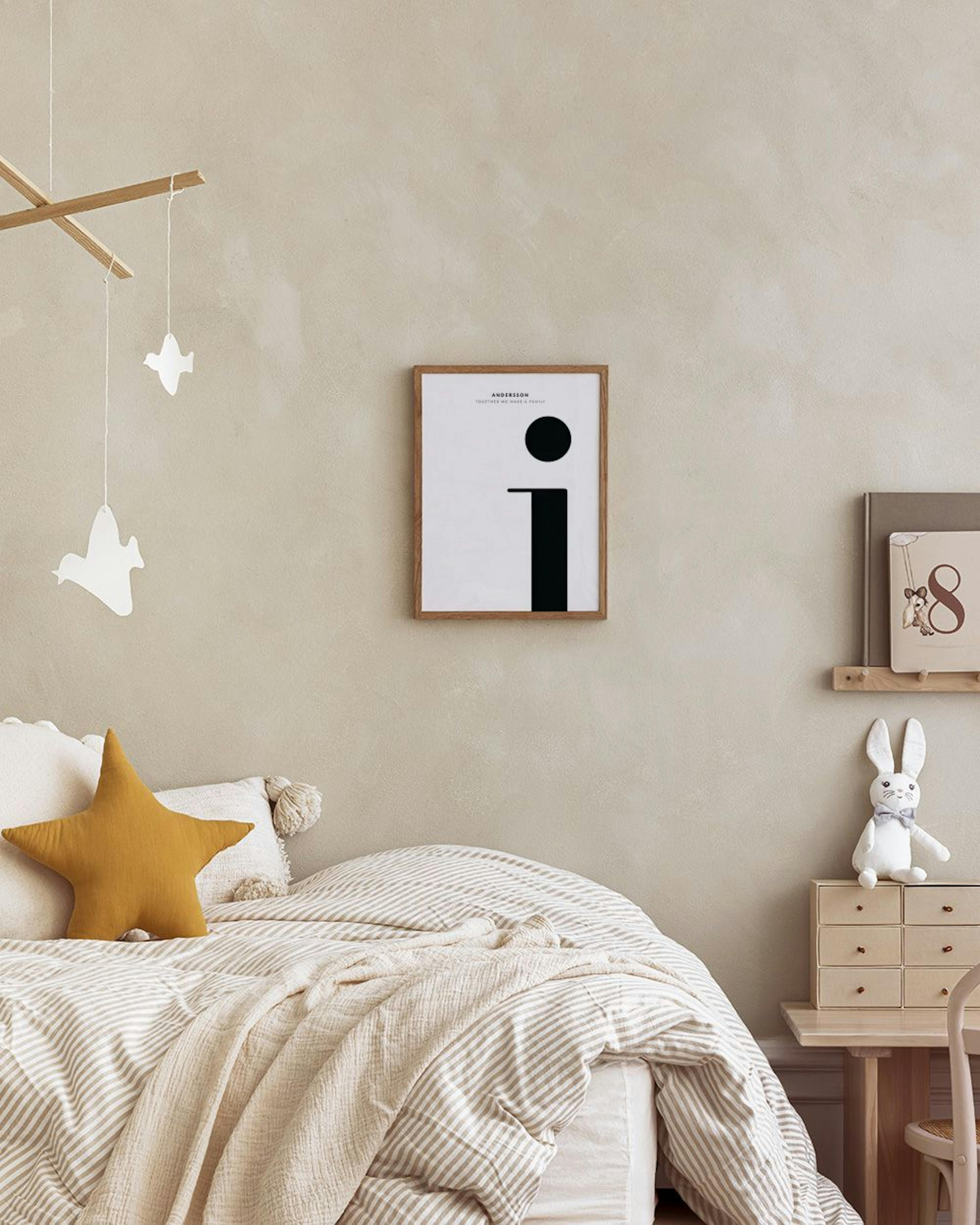 A personalized print with a black letter i and text, displayed above a wooden cane cabinet with books and decor.