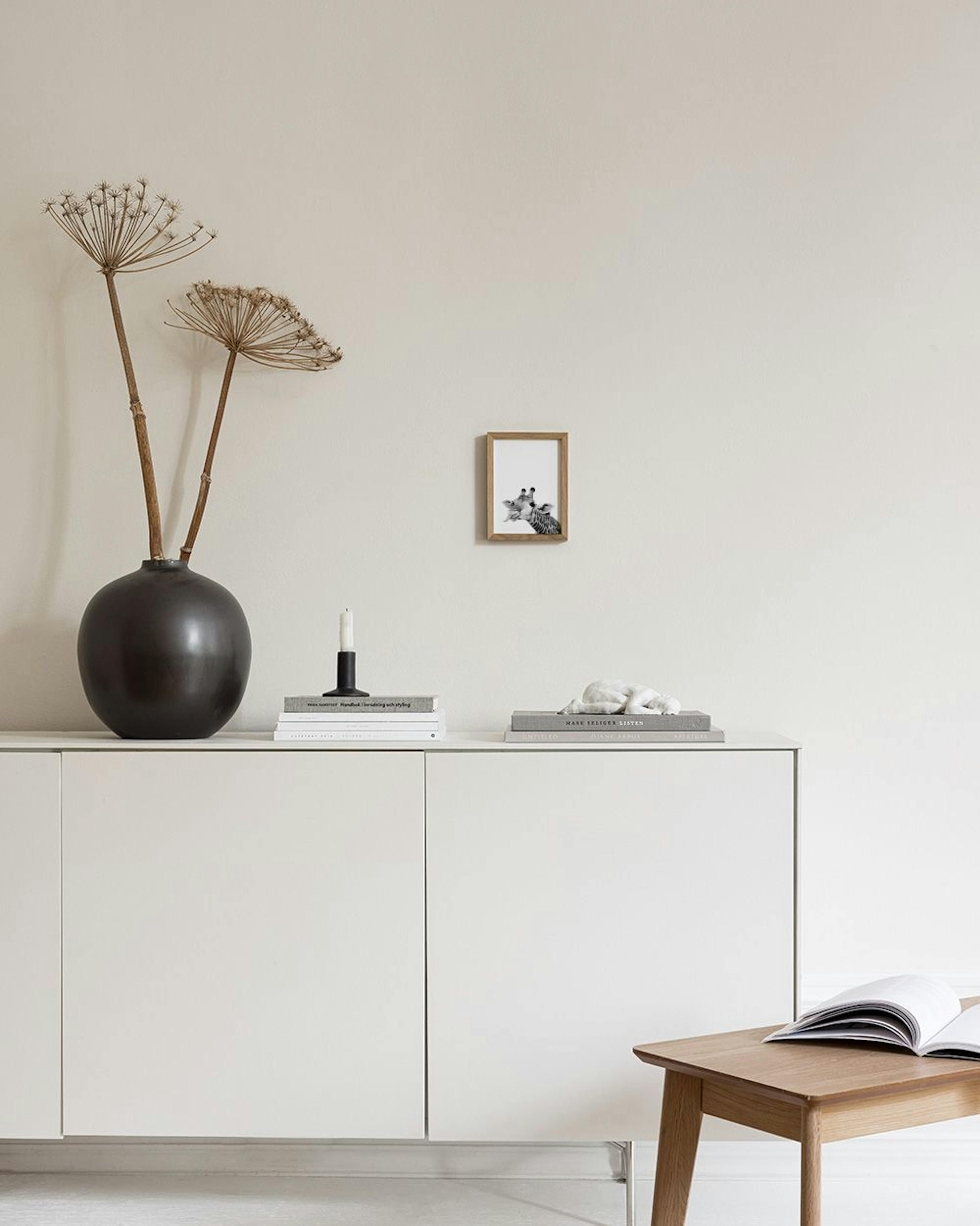 Affiche murale en noir et blanc dune girafe tirant la langue, exposée sur une commode blanche avec des décorations.
