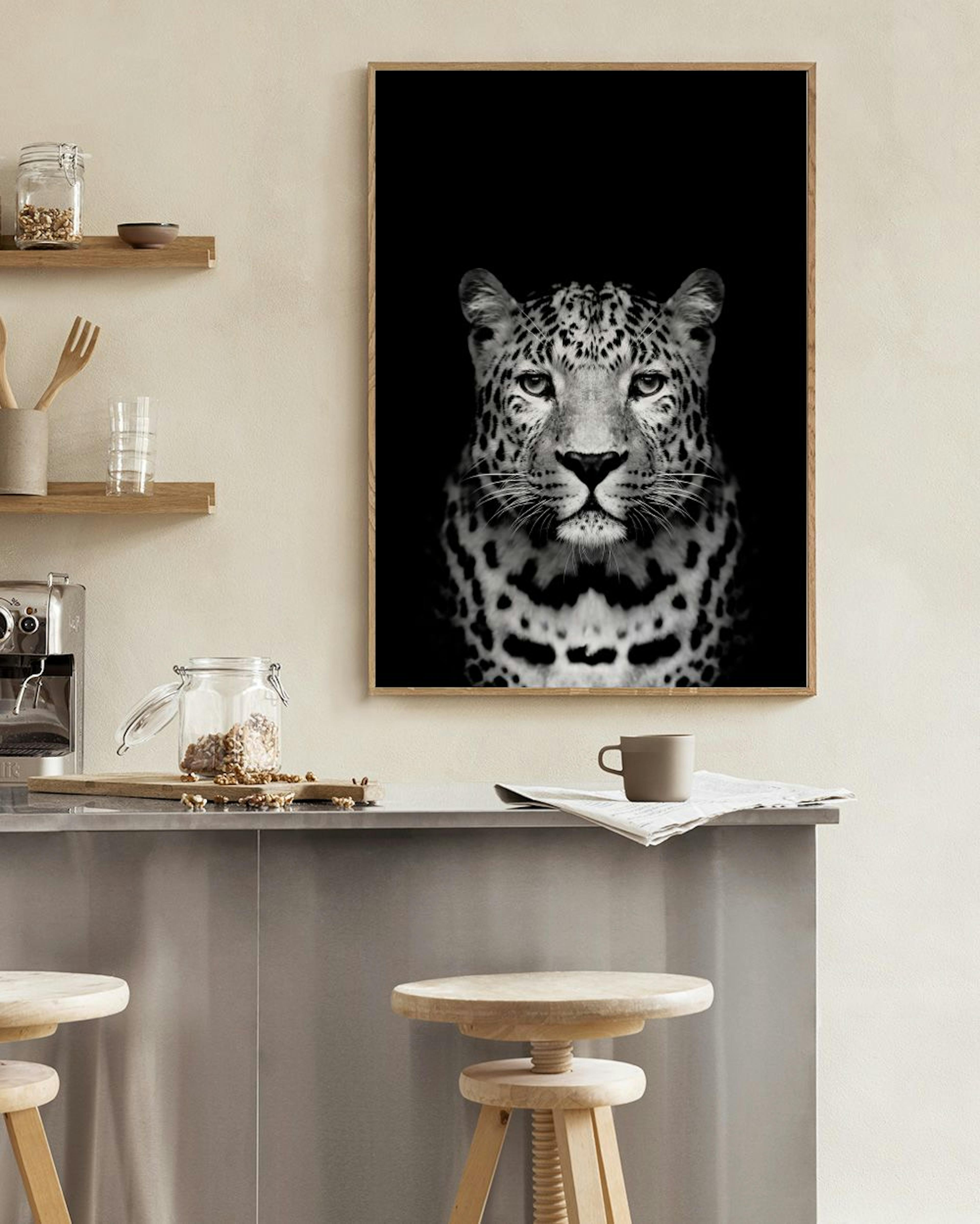 Póster de un leopardo en blanco y negro, con la cara frontal y mirada directa, colgado en una pared azul oscuro sobre un taburet