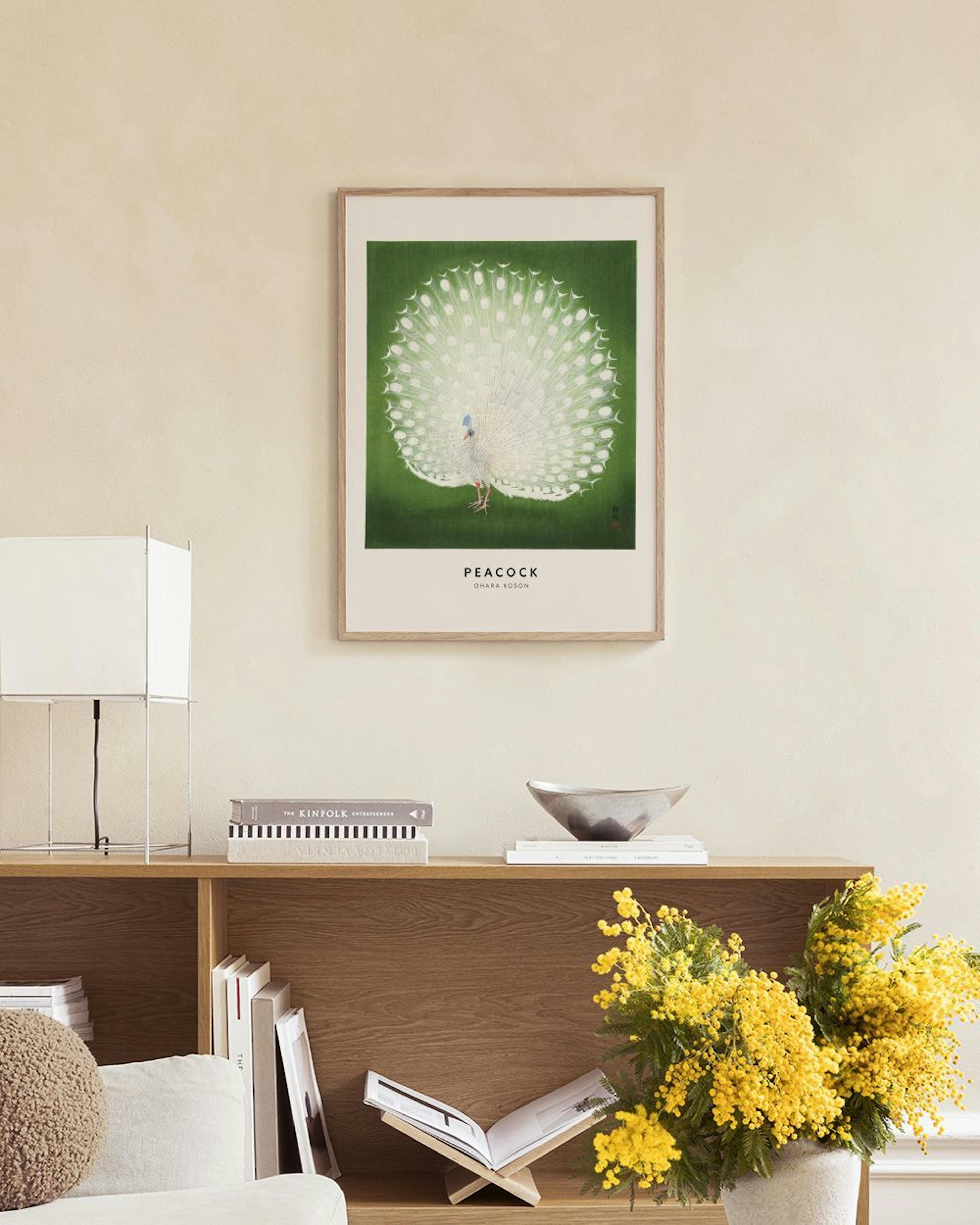 A print of a white peacock with a fanned tail on a green background, displayed above a white cabinet with decorative vases and b
