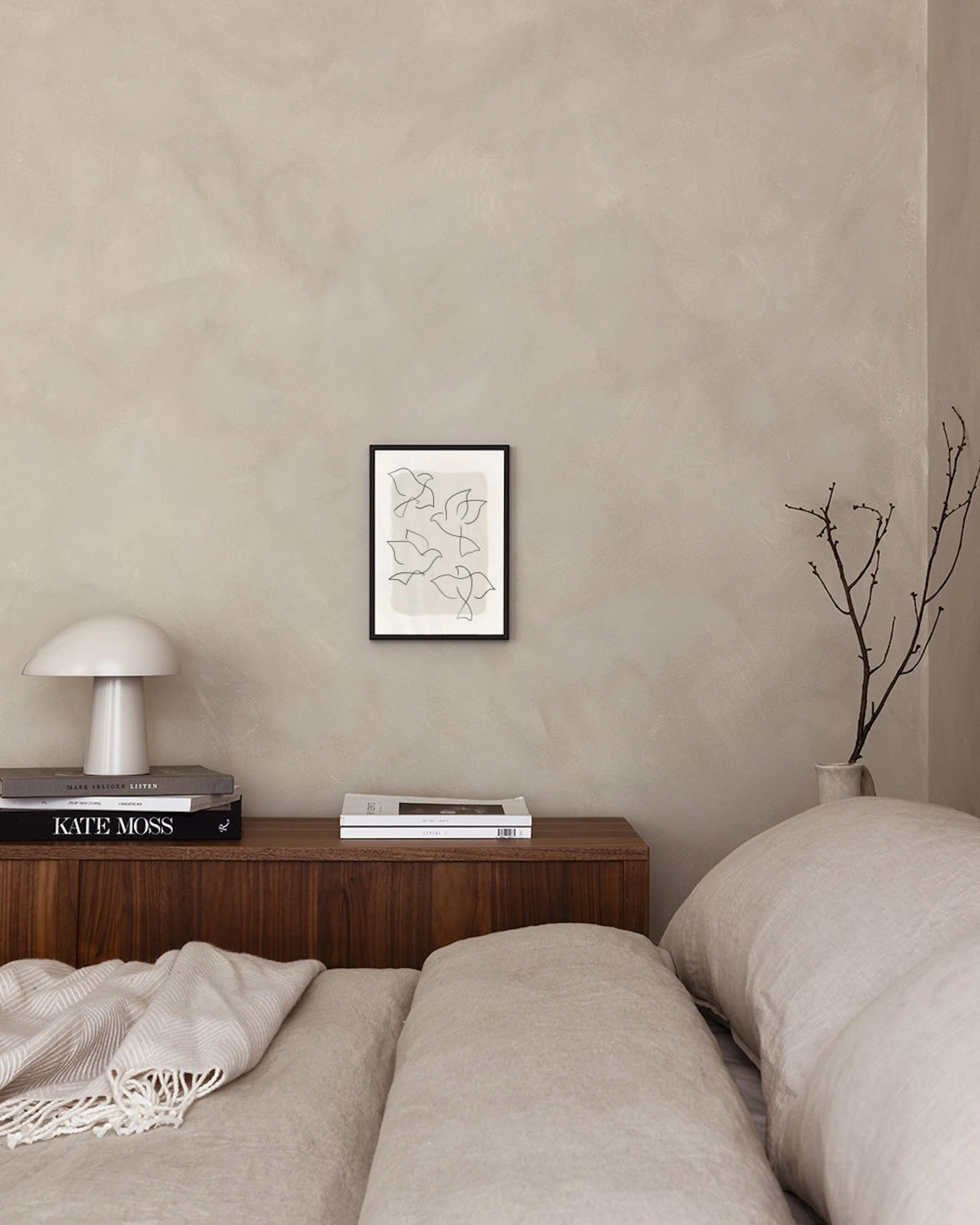 Poster mit minimalistischer Linienzeichnung fliegender Vögel über einem Sideboard mit Vase und Buch.