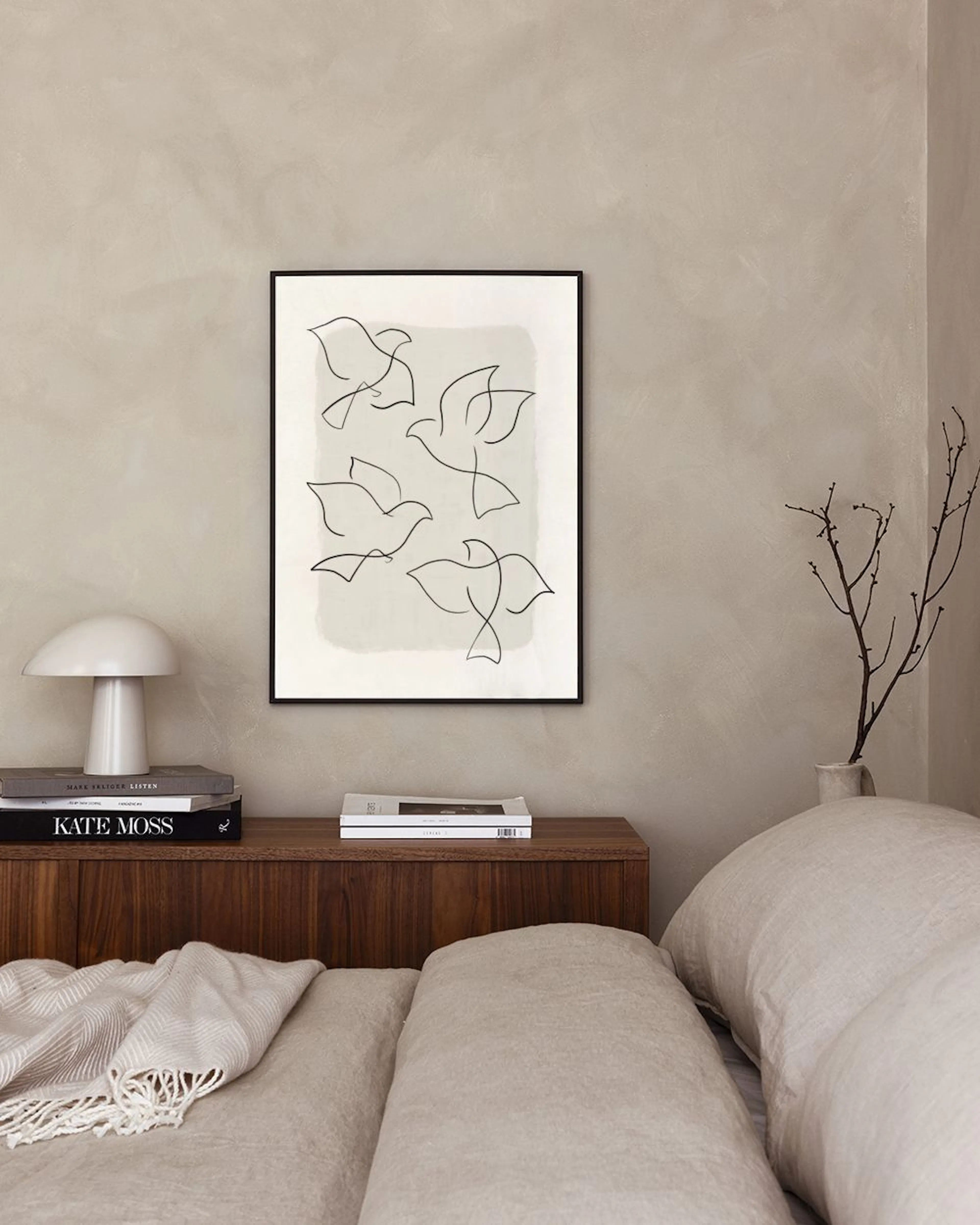 Poster met lijntekening van vijf duiven op een lichte achtergrond, boven een wit dressoir met vaas en boek.