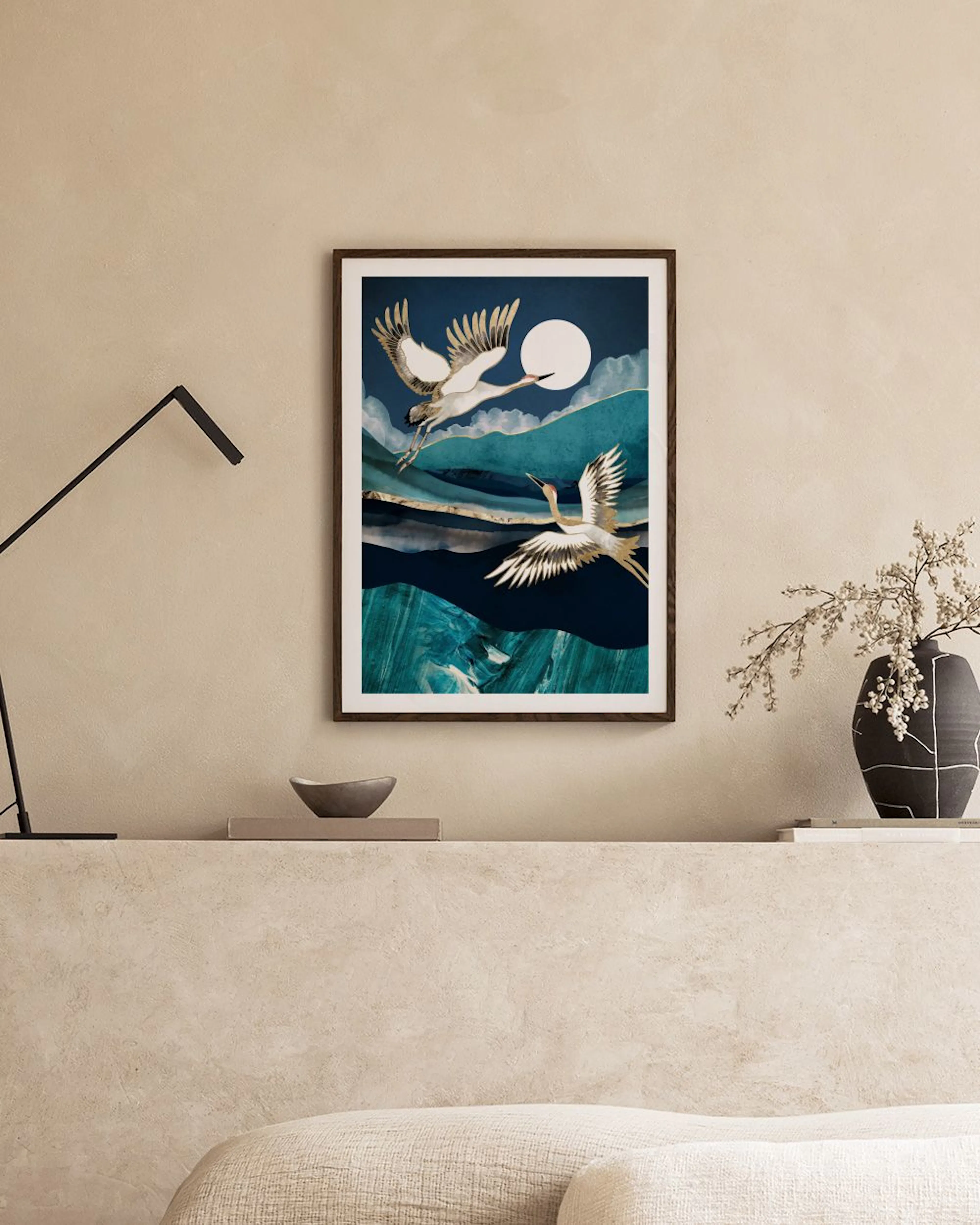 Affiche avec deux grues blanches et dorées volant devant une pleine lune sur des collines bleues, affichée au-dessus dun bureau 